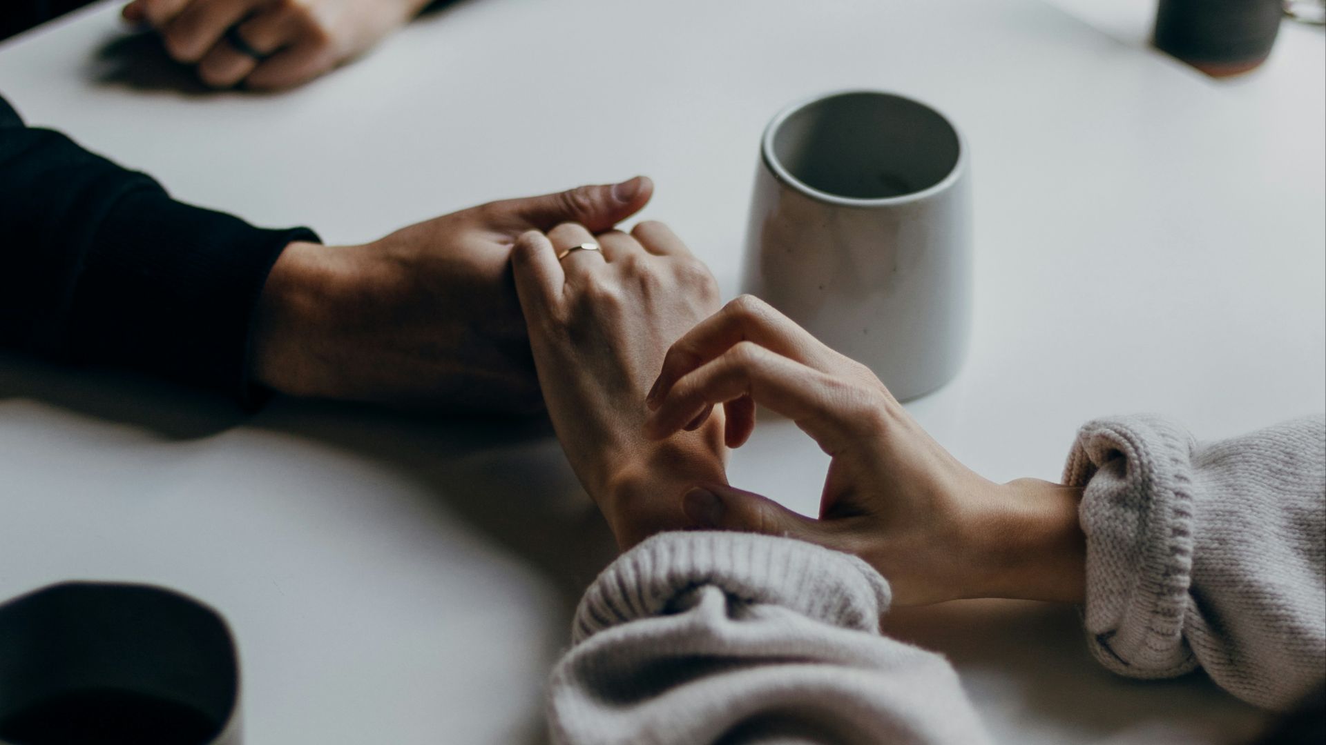 person in black long sleeve shirt holding white ceramic mug