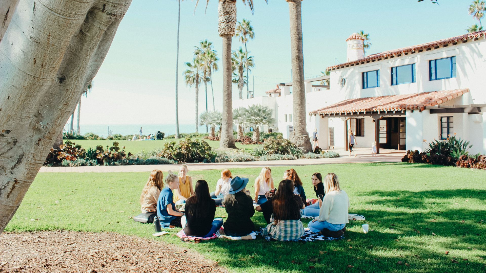 people sitting on ground while forming round during daytime