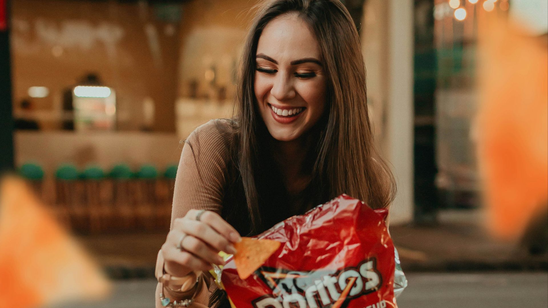 woman in black shirt sitting on the street holding red plastic pack