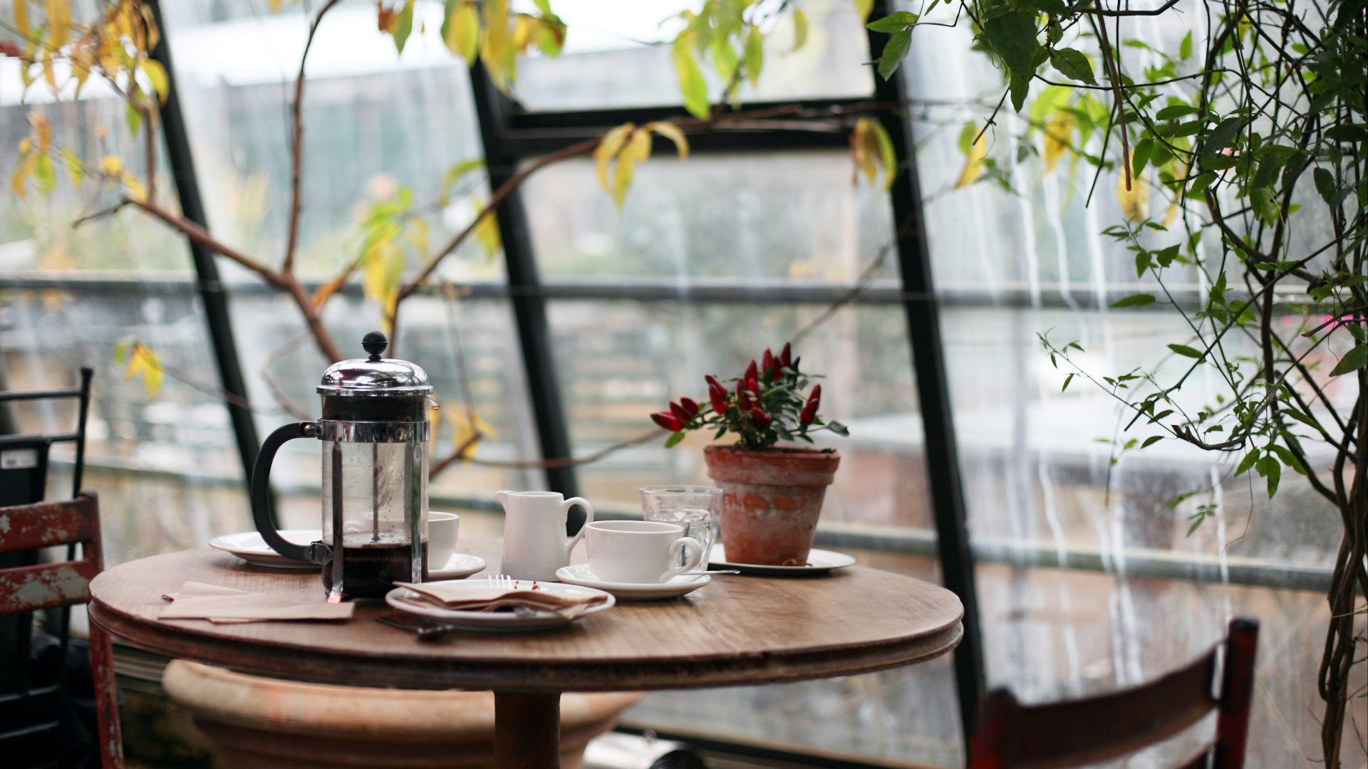 round brown wooden table with french press on top with white ceramic teacup beside