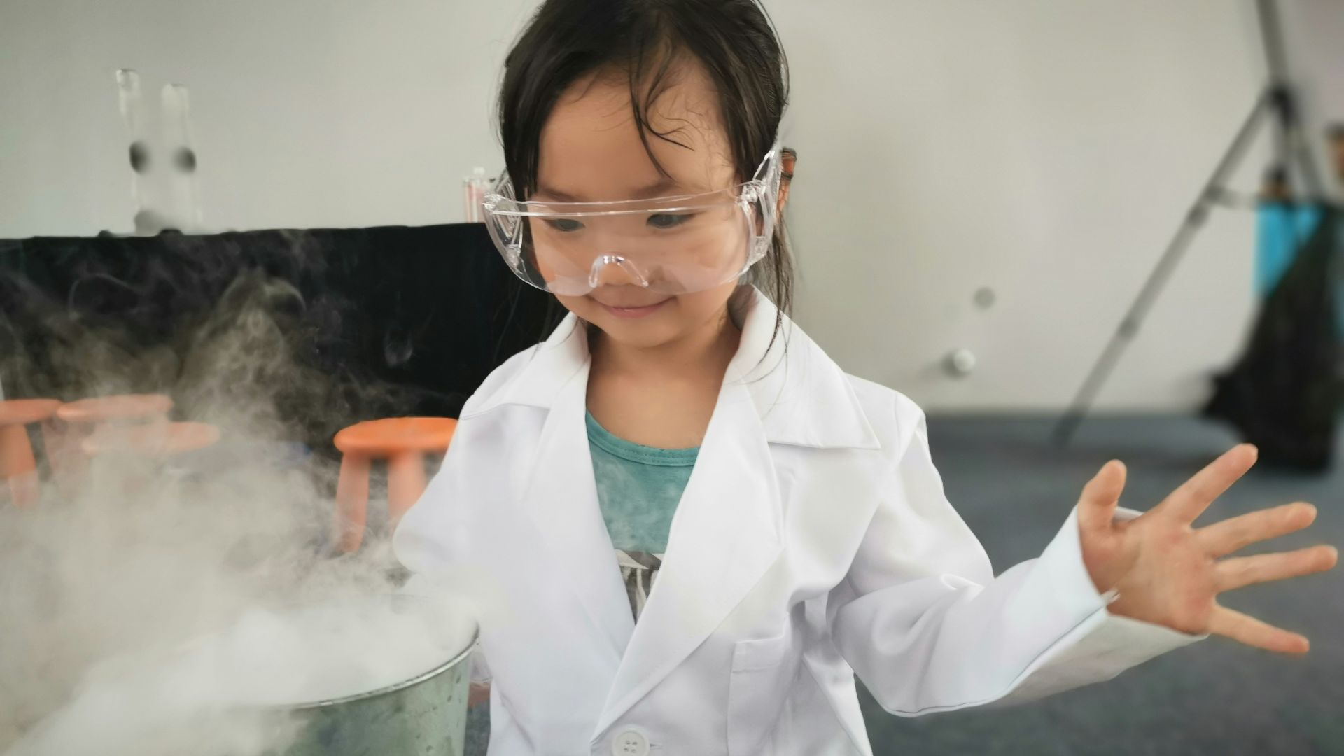 a little girl wearing a white lab coat and goggles