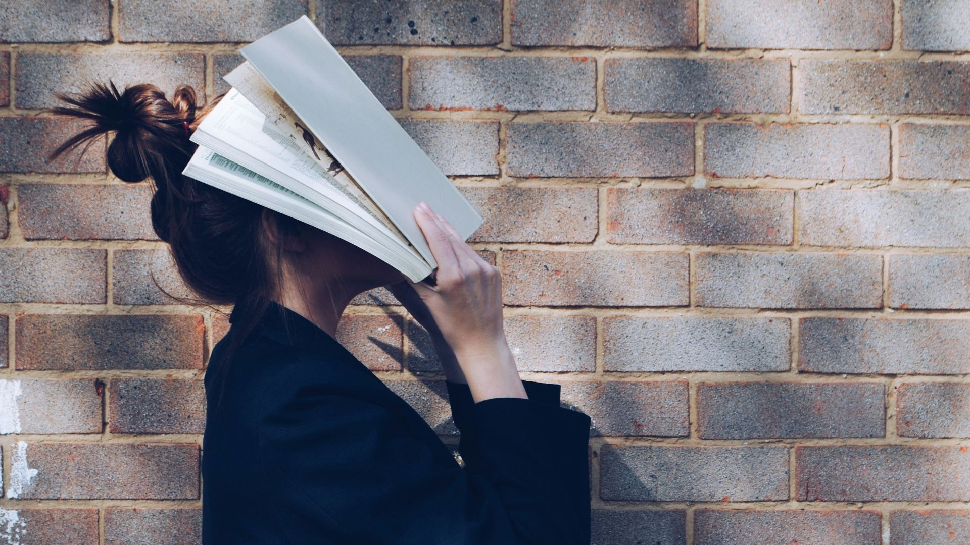 woman covering her face with white book