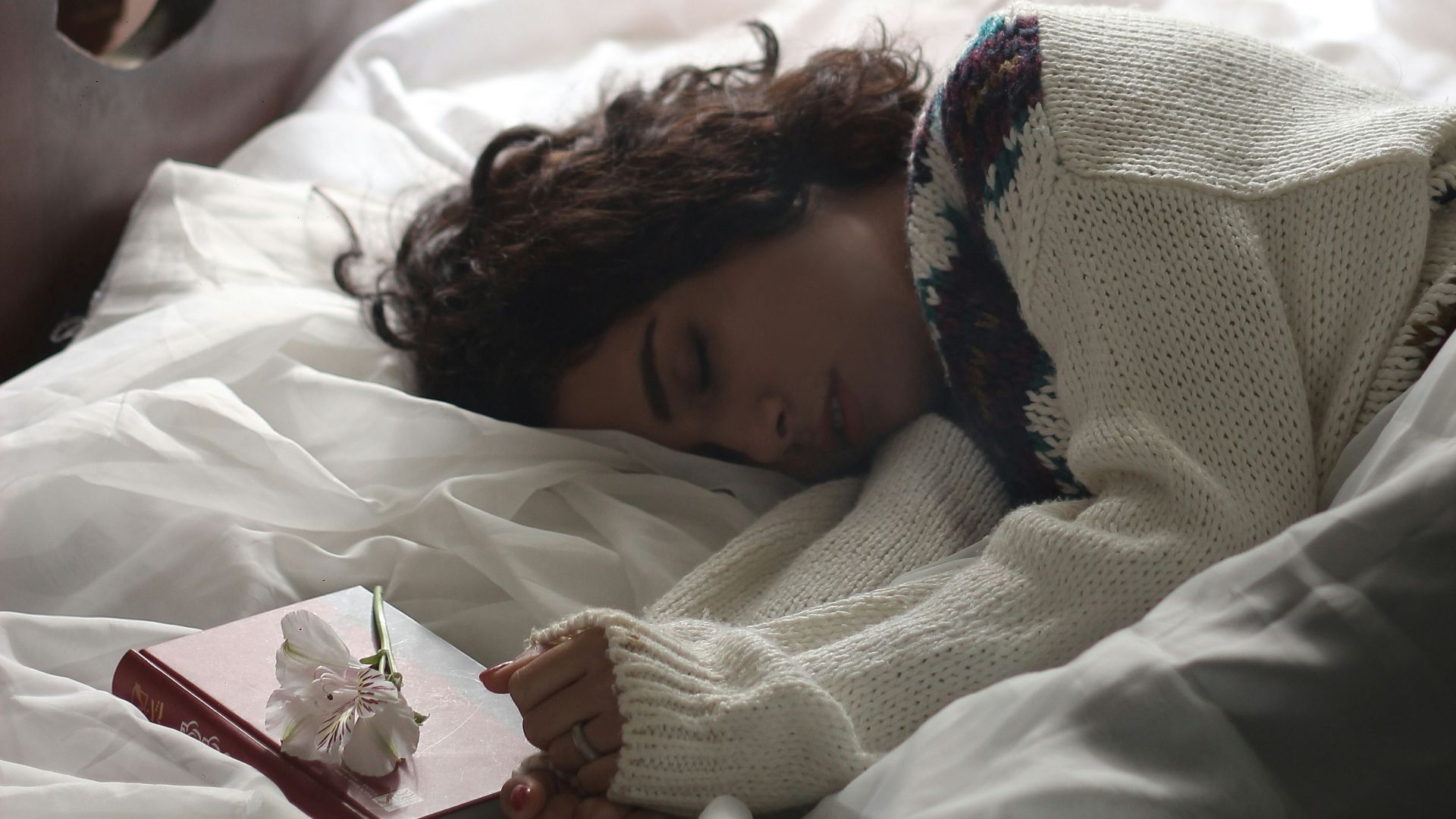 woman sleeping on bed beside book