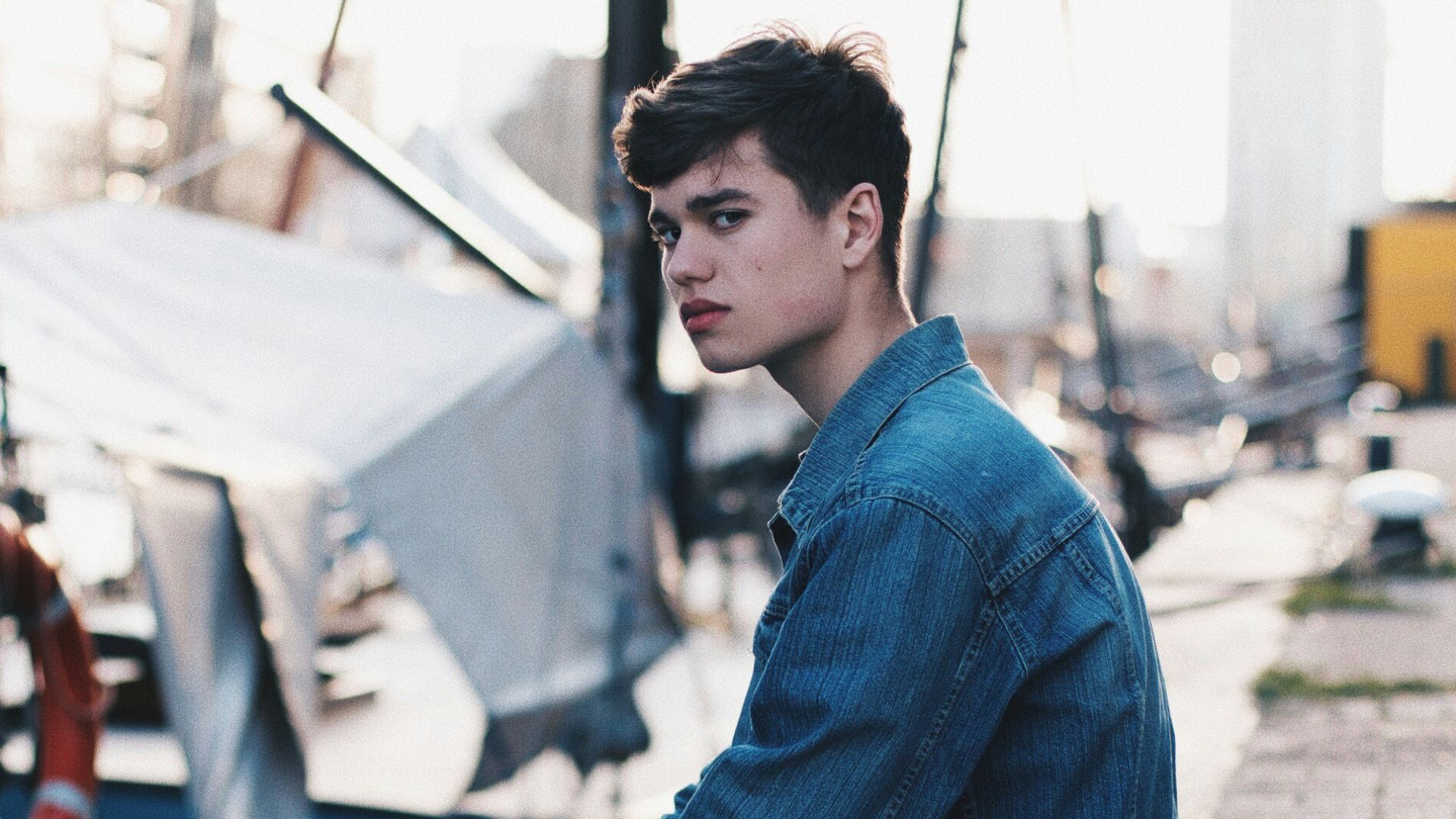 man in blue denim jacket sitting on dock