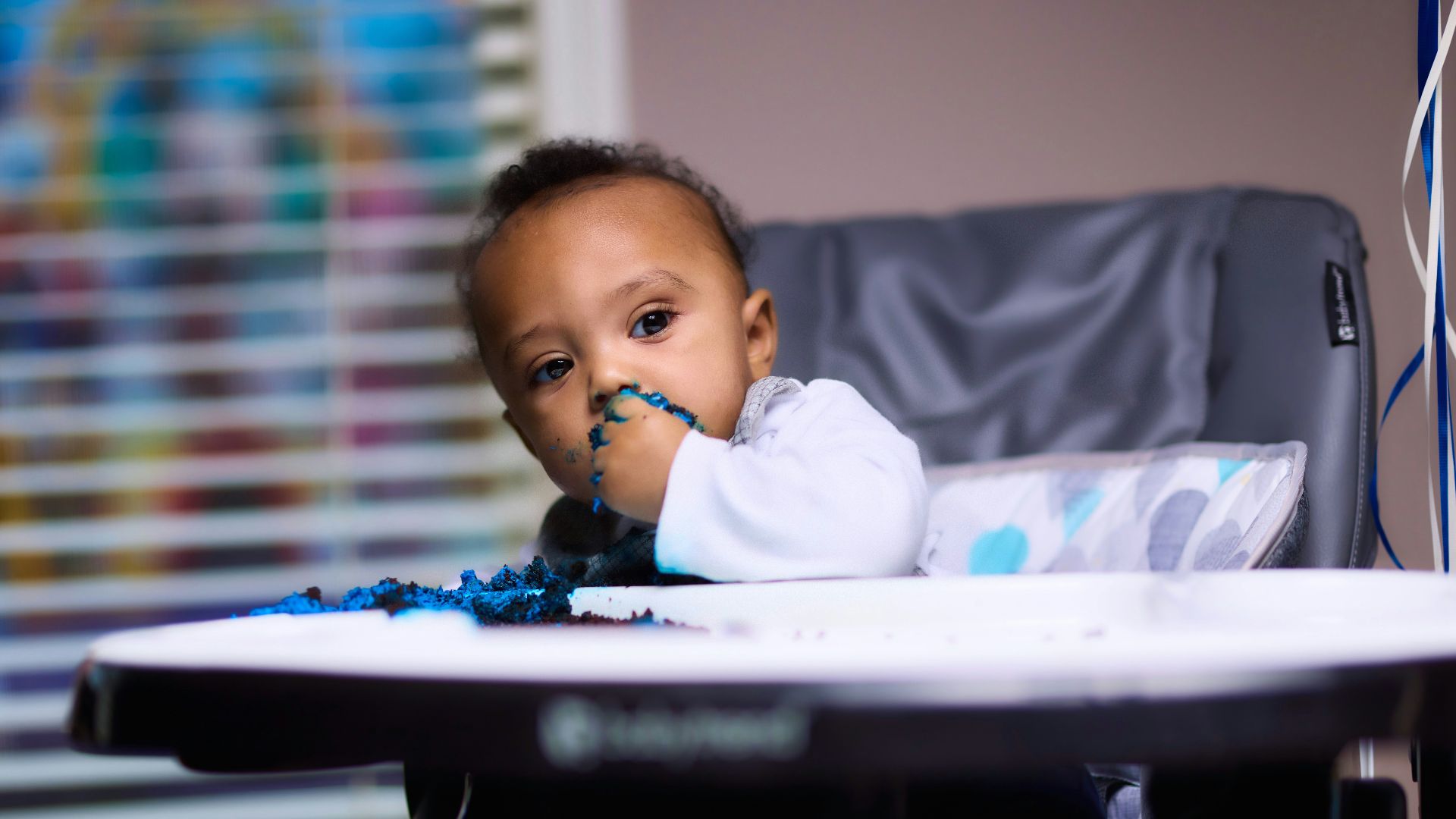 baby in white long sleeve shirt sitting on white high chair