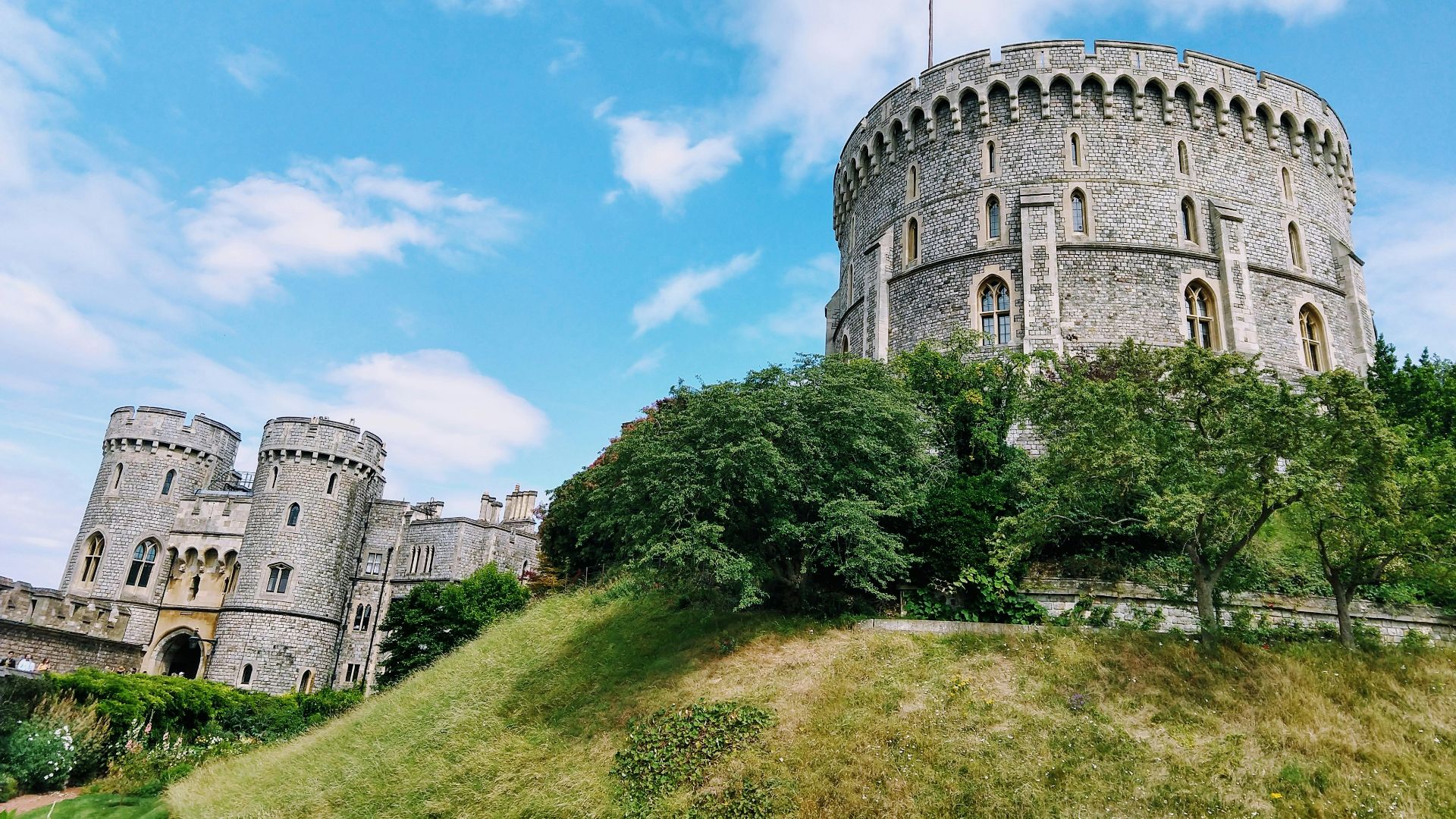 grey concrete building on green grass field under blue sky during daytime