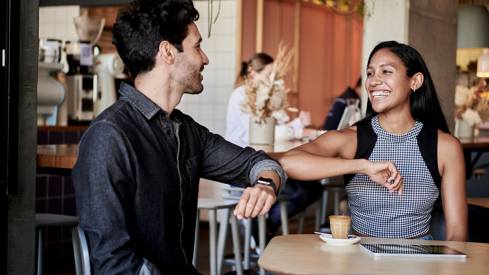 man in black shirt elbow bumping with woman in a restaurant