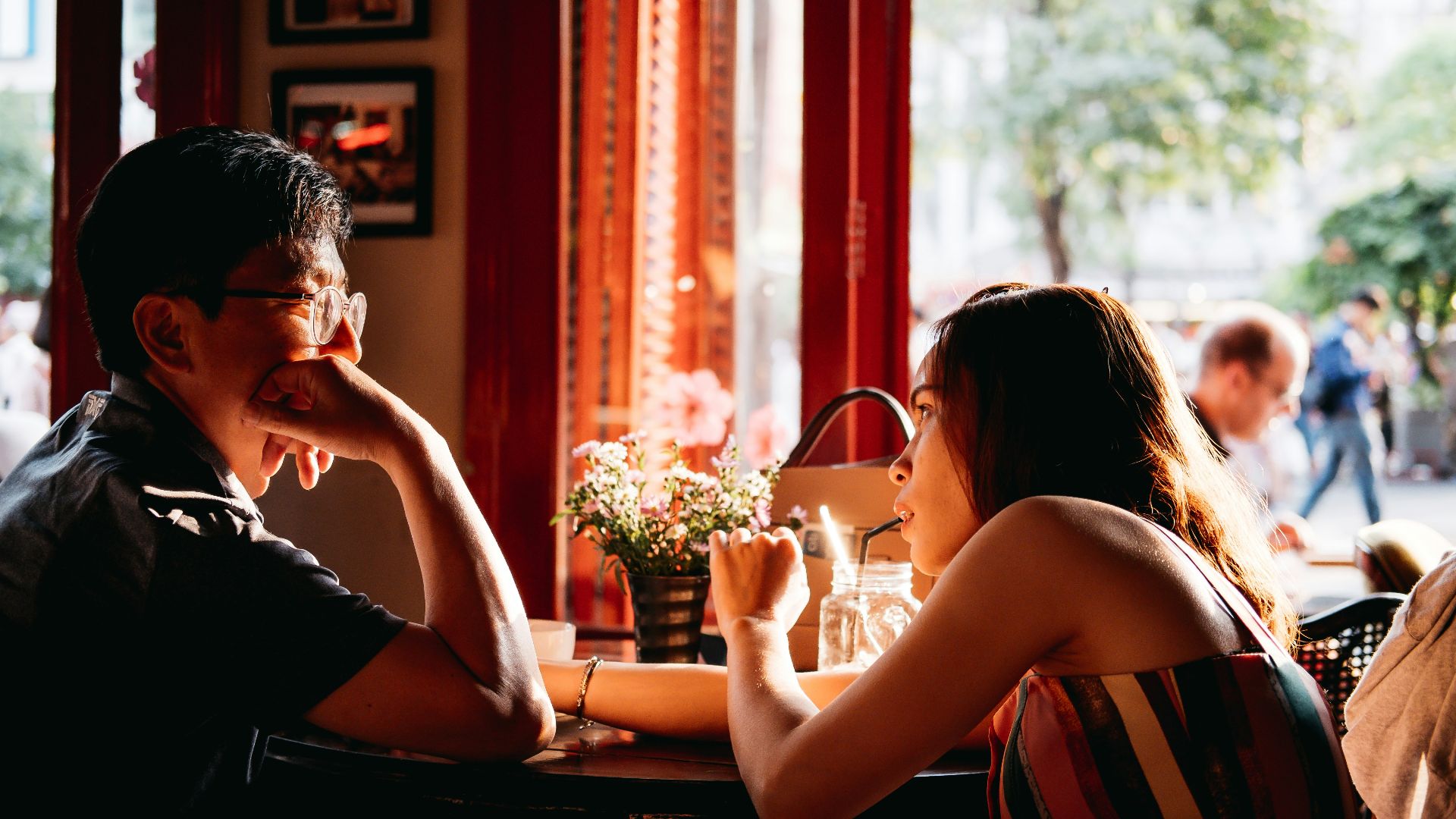 man wearing black collared top sitting on chair in front of table and woman wearing multicolored top