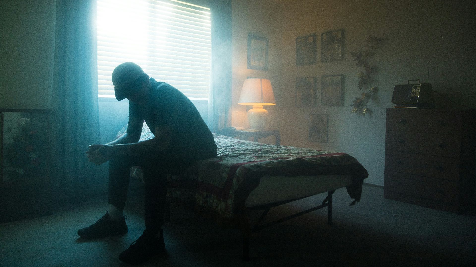 man in black jacket sitting on bed