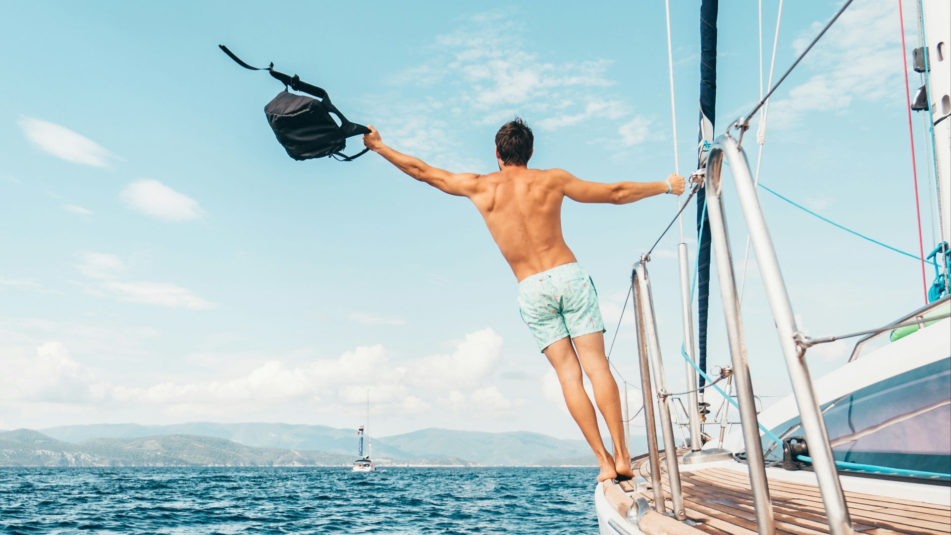 man wearing white shorts holding black backpack