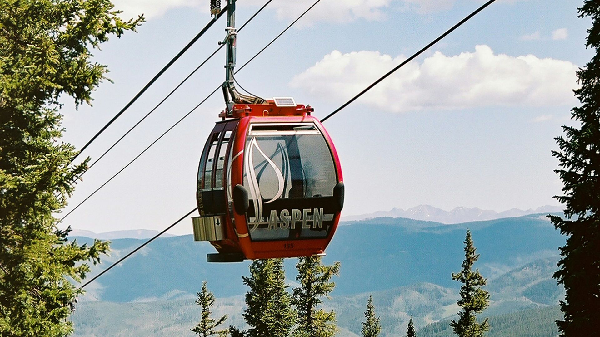 red cable car over green trees during daytime