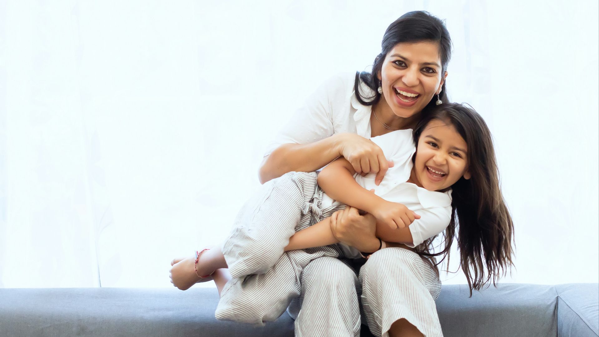 2 women sitting on gray couch