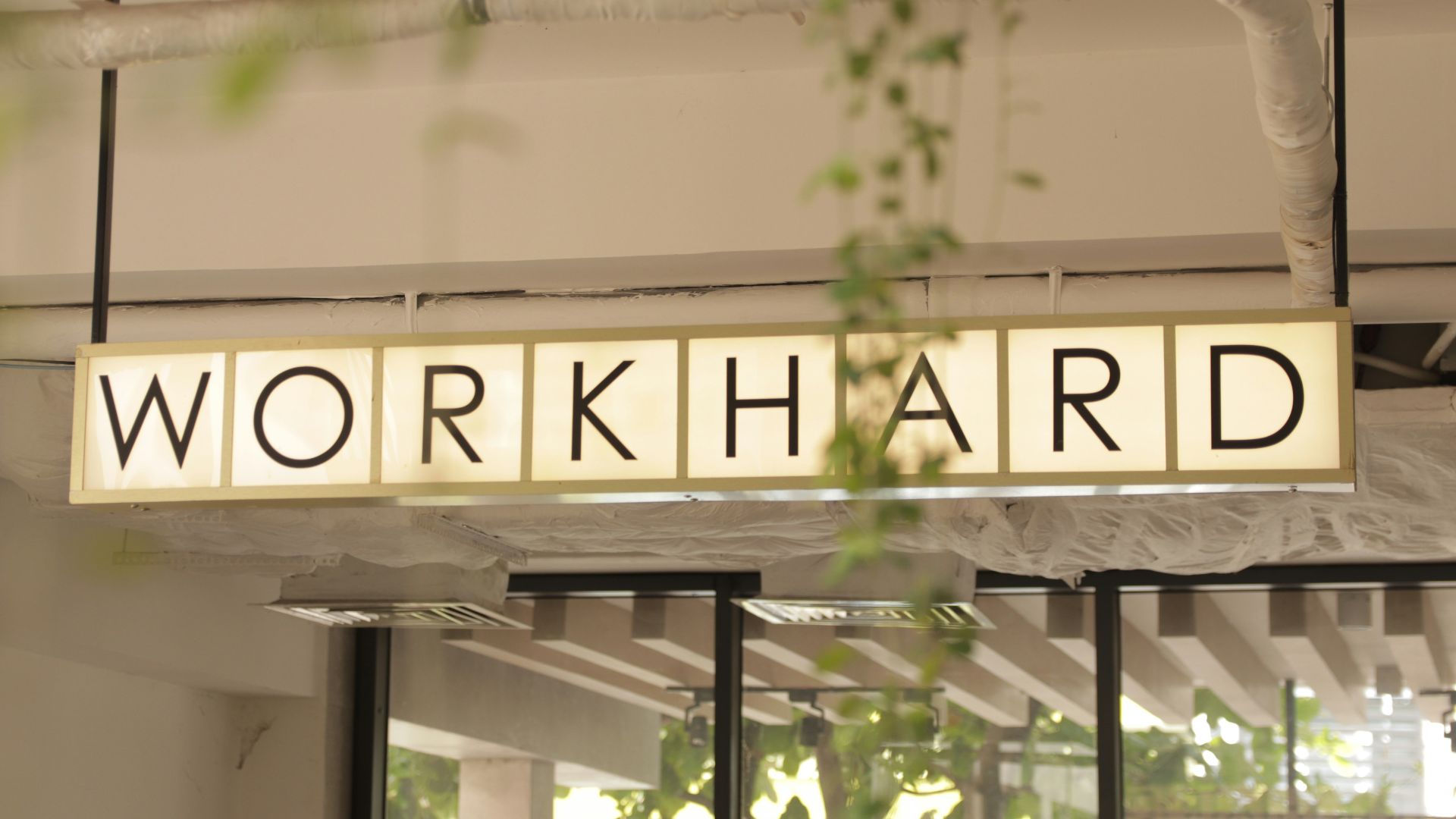 a sign that reads work hard hanging from a ceiling