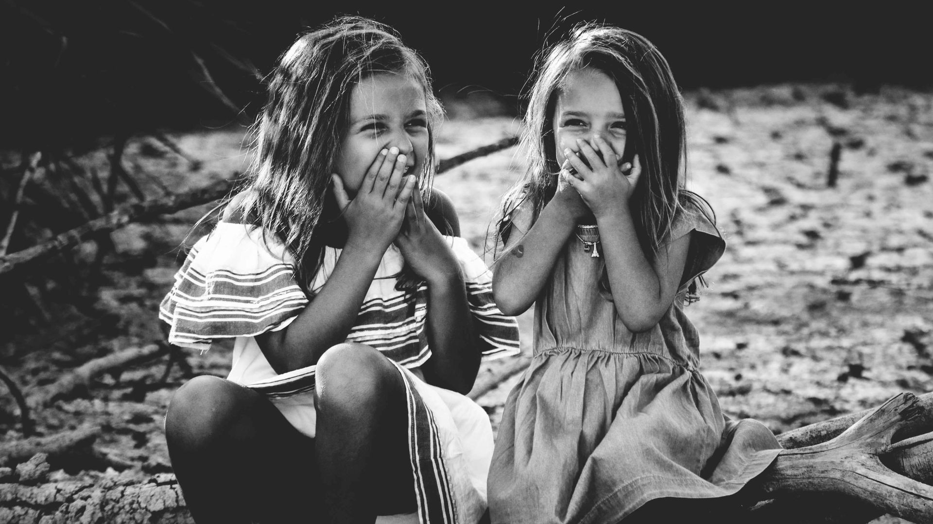 grayscale photography of two girls closing their mouths