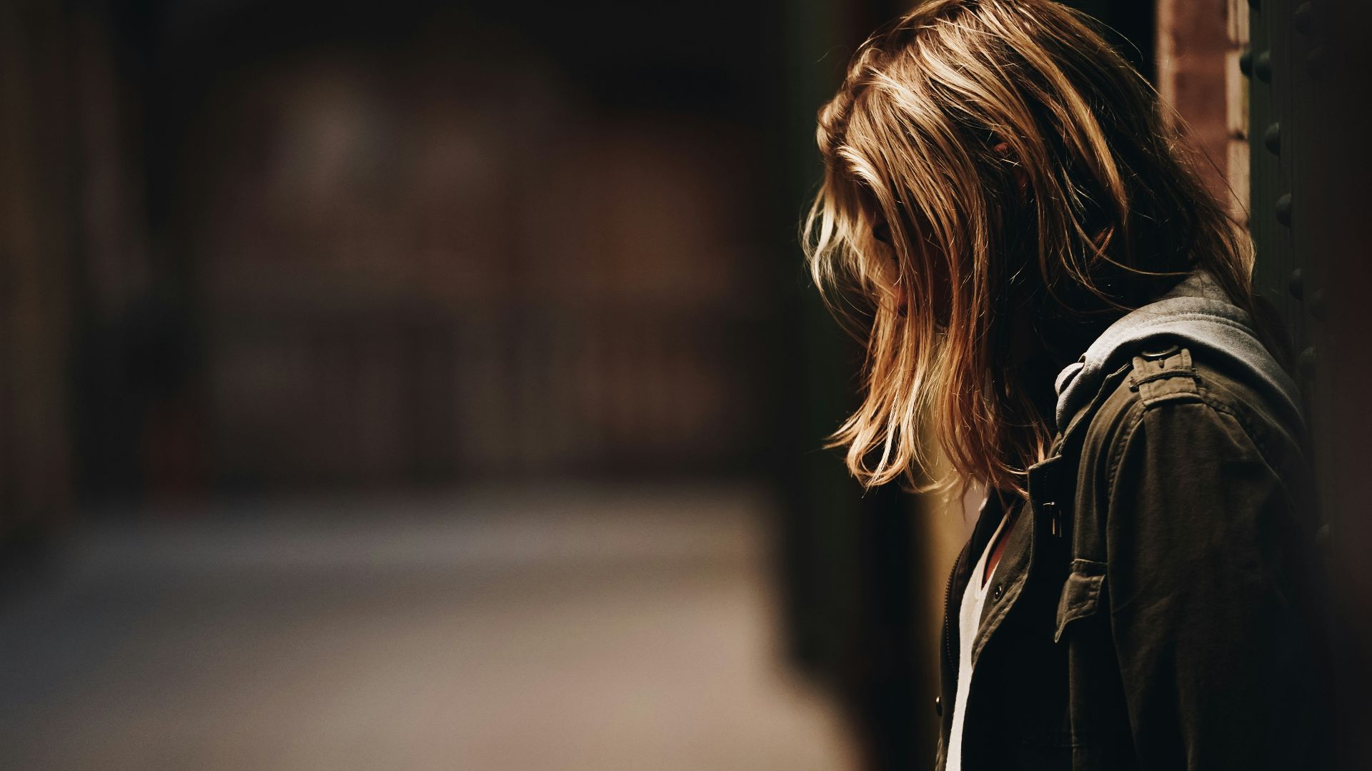 woman leaning against a wall in dim hallway