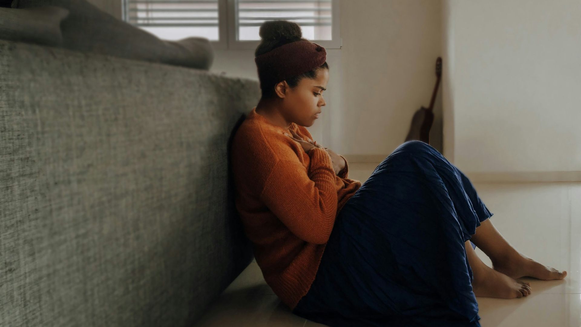man in orange long sleeve shirt sitting on gray couch