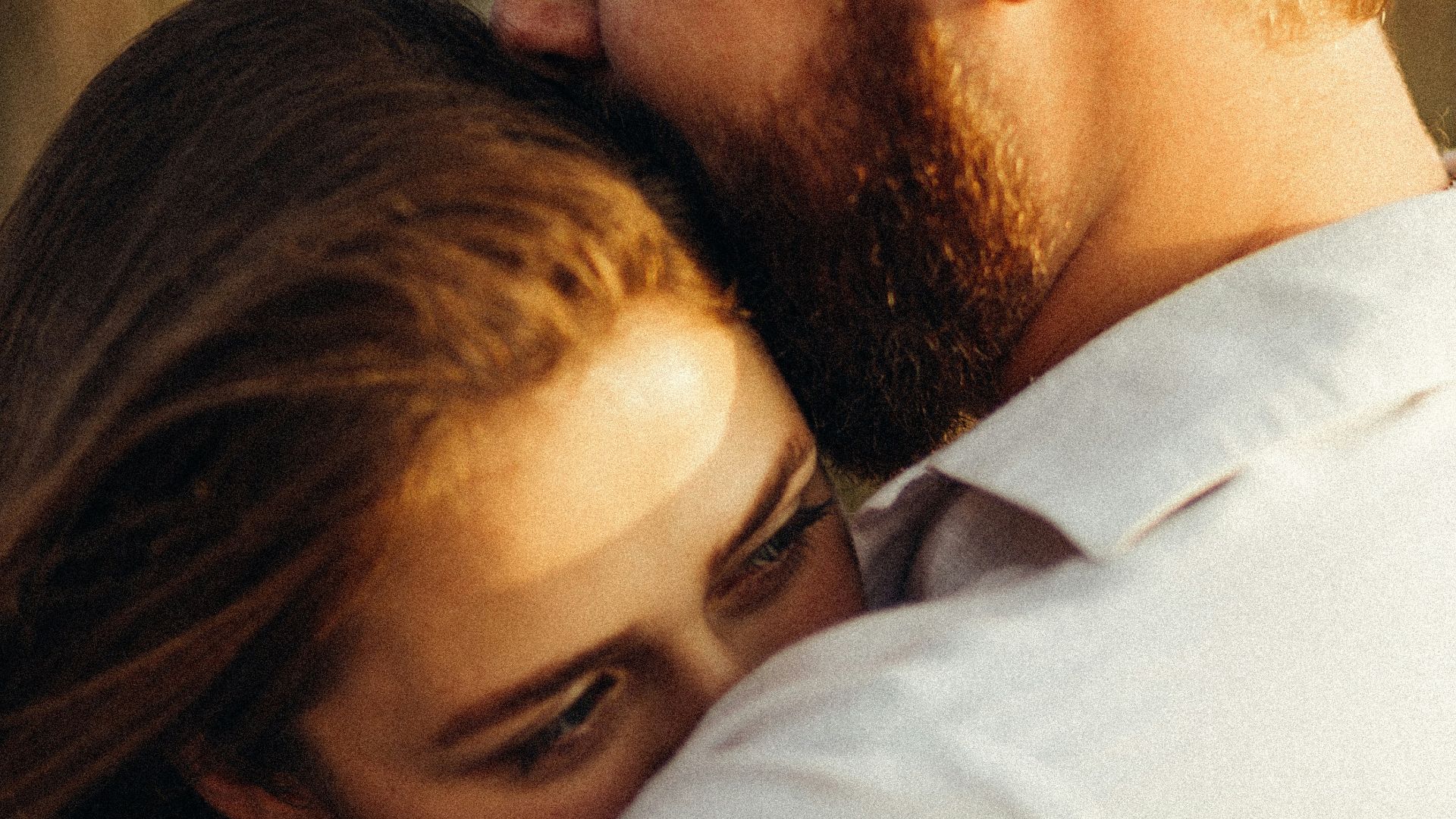 man in white dress shirt kissing woman in black hair