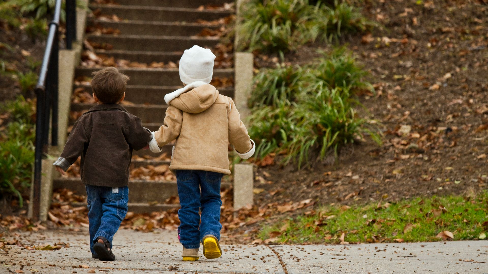 two toddlers walking towards stairs