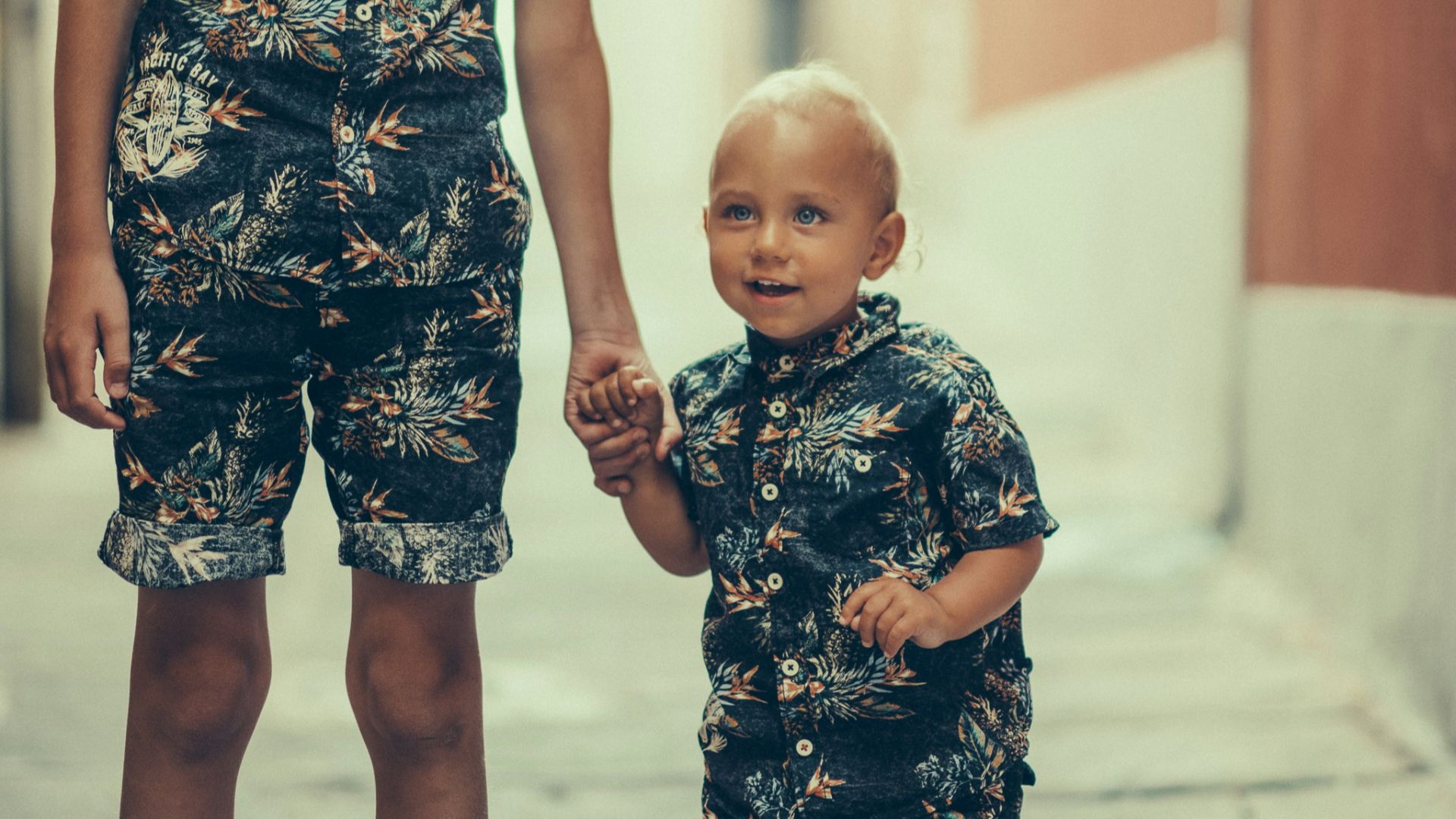 matching pair of boy's black and gray floral collared shirt and shorts standing on gray concrete area