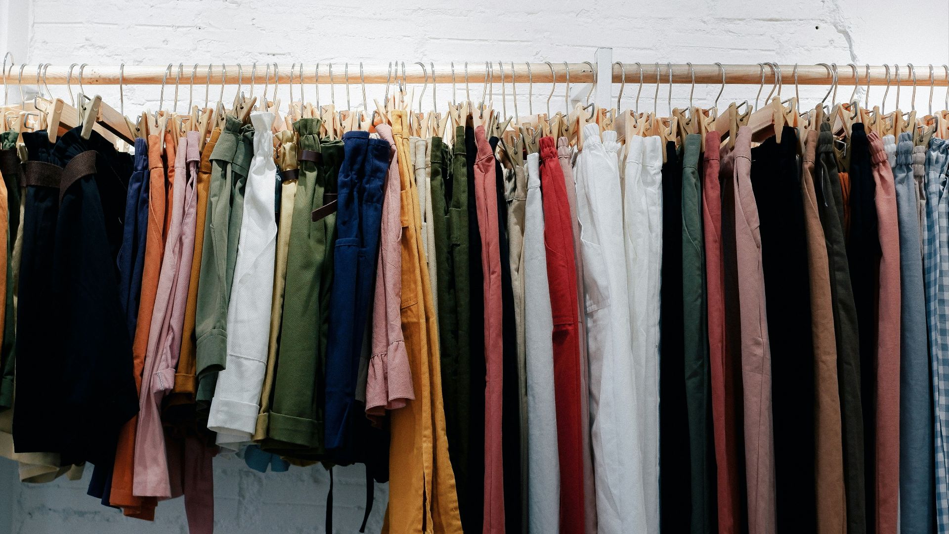 assorted-color clothes lot hanging on wooden wall rack
