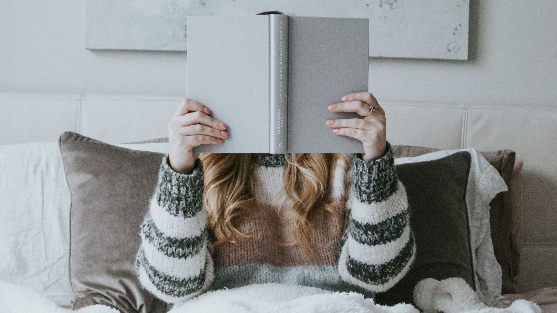 woman sitting on bed while holding book