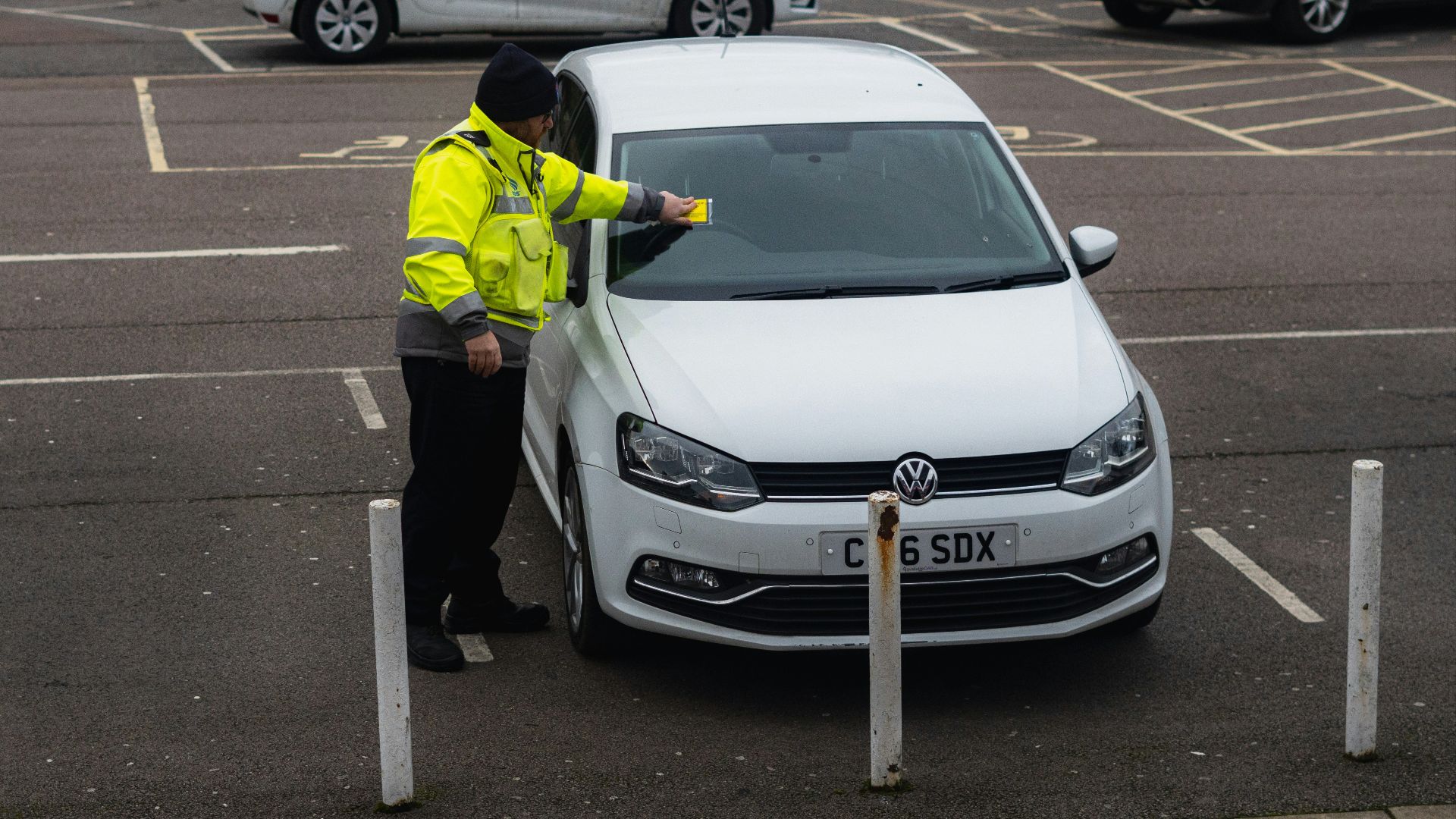 man in yellow jacket standing beside white car