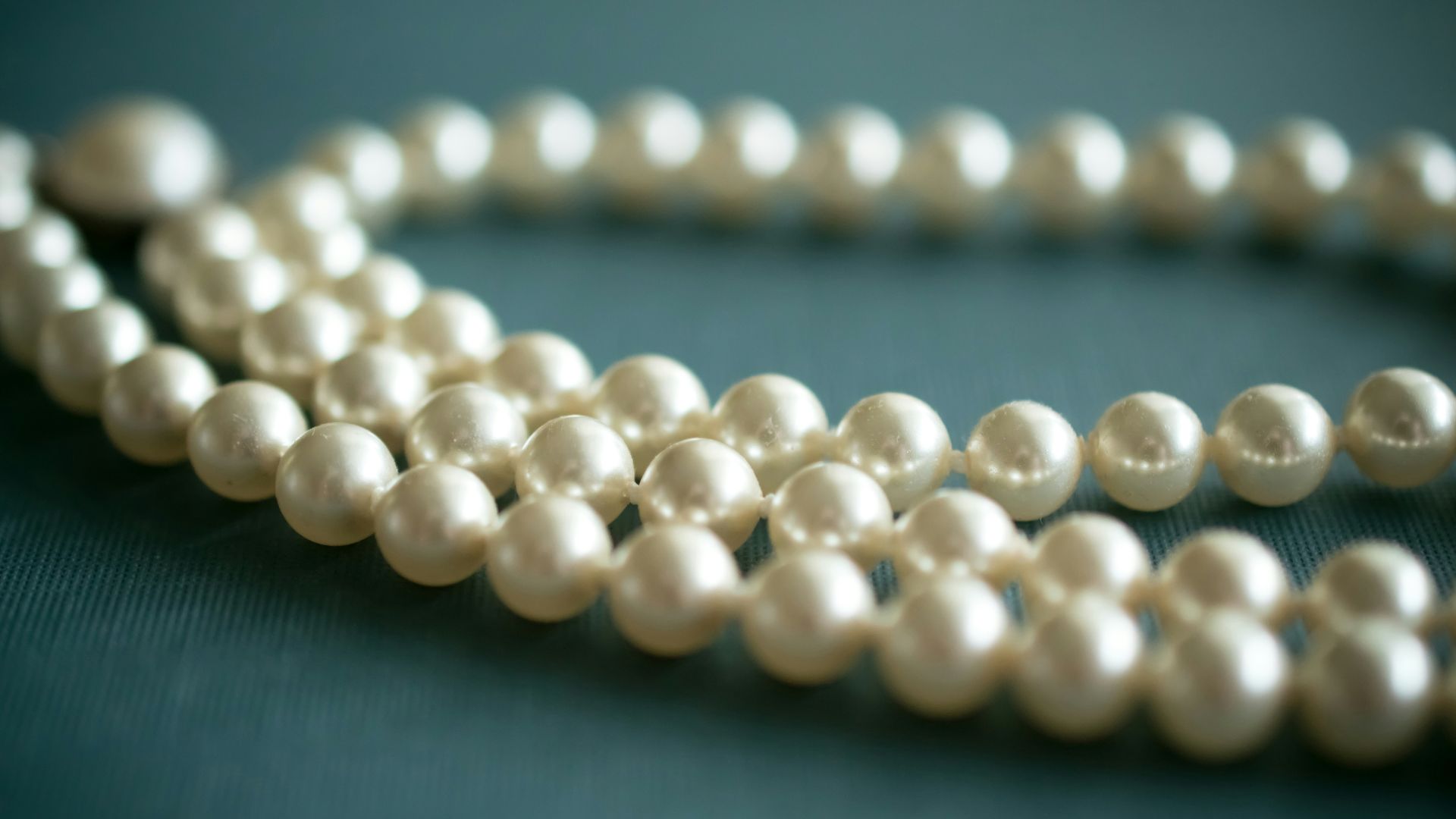 white pearl necklace on gray textile