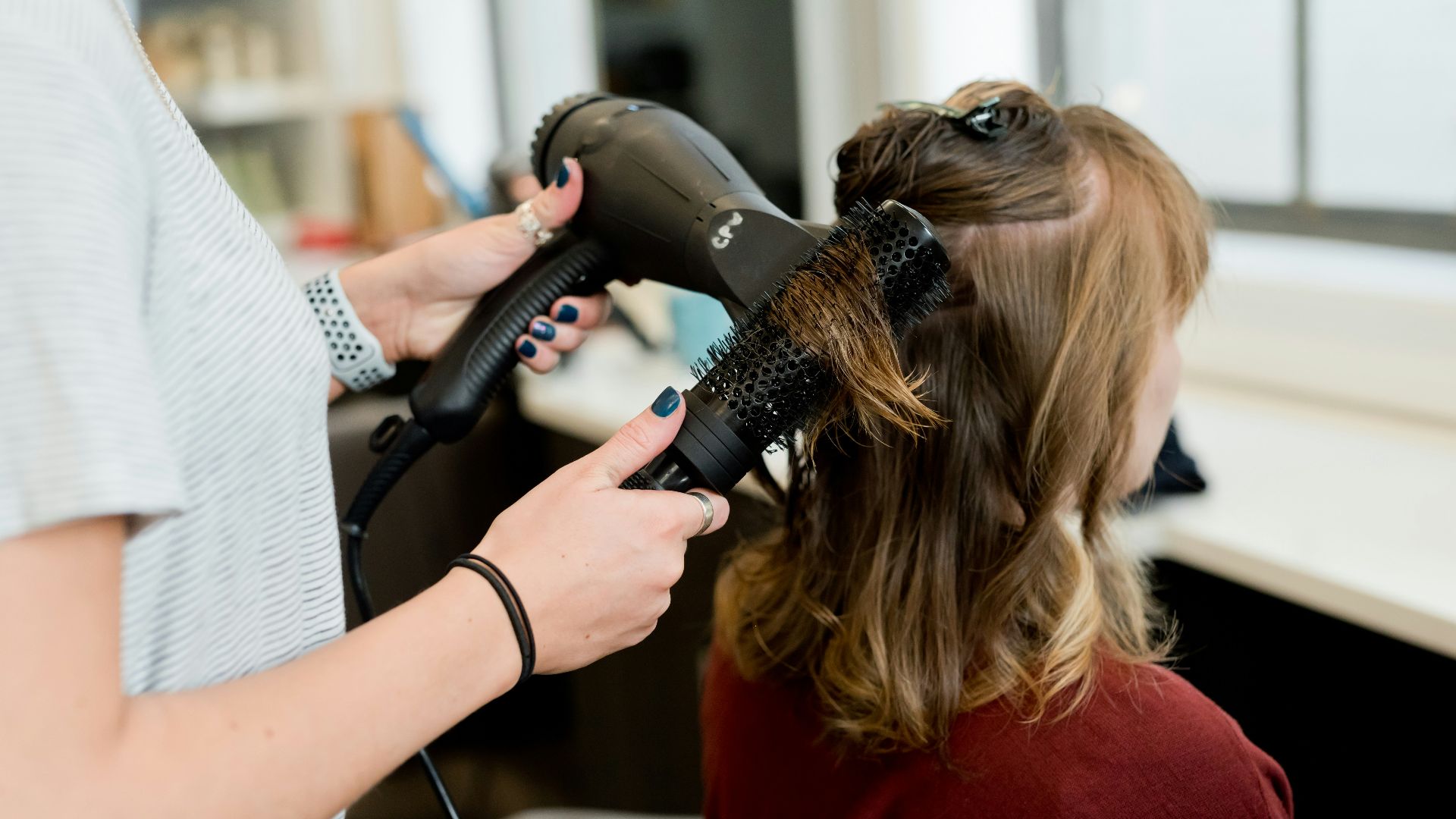 woman in red long sleeve shirt holding hair blower