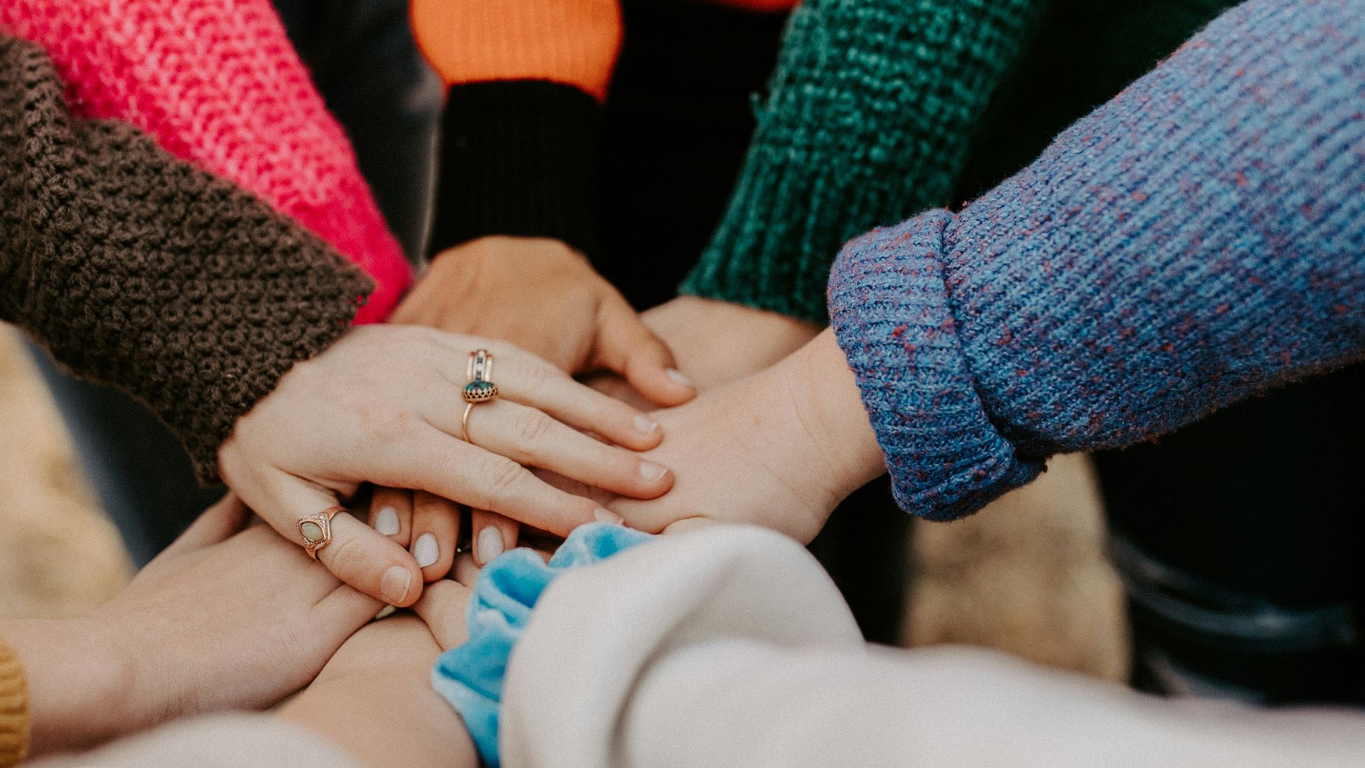 person in red sweater holding babys hand
