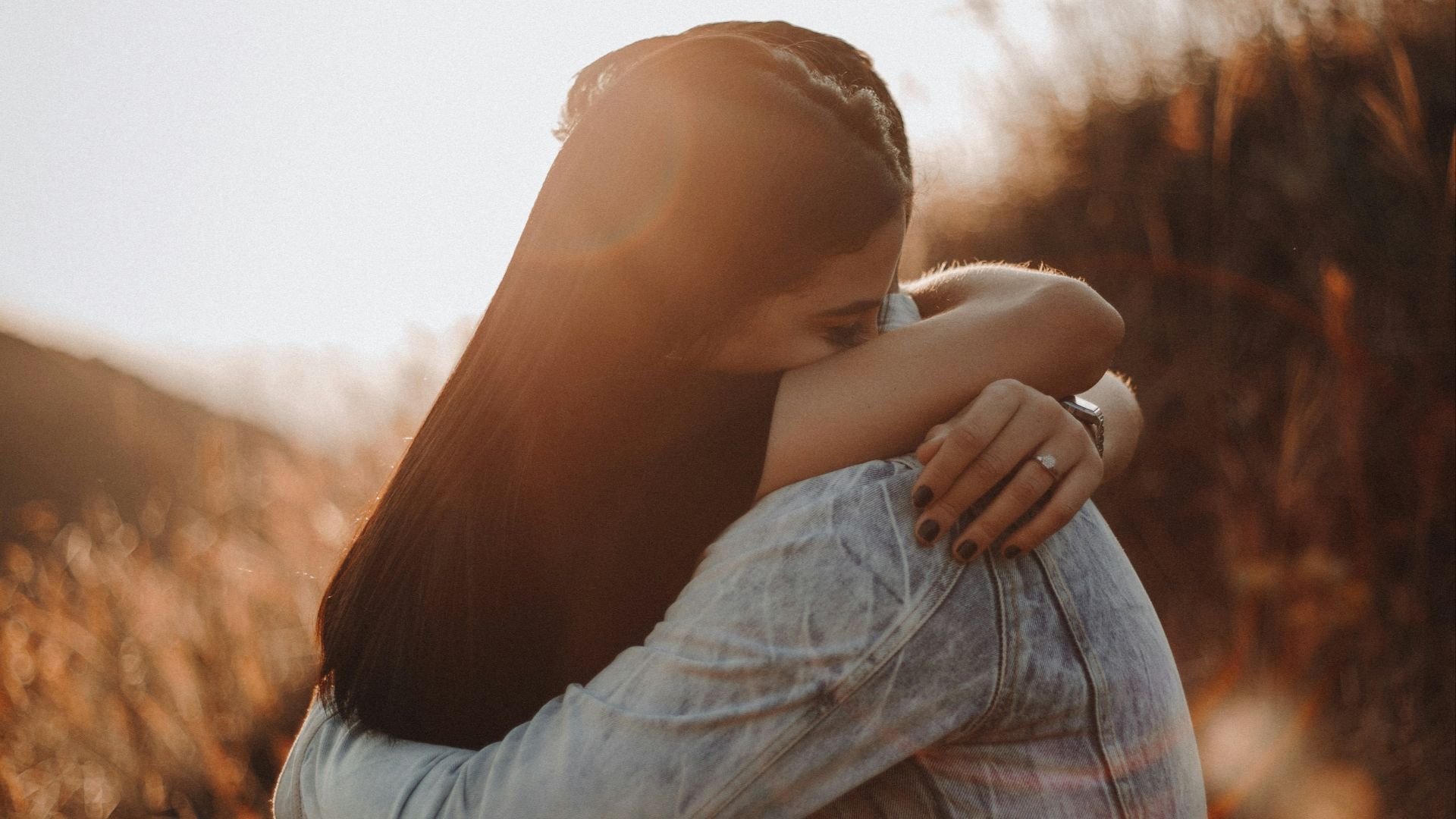 woman in black long sleeve shirt and blue denim jeans covering her face with her hand
