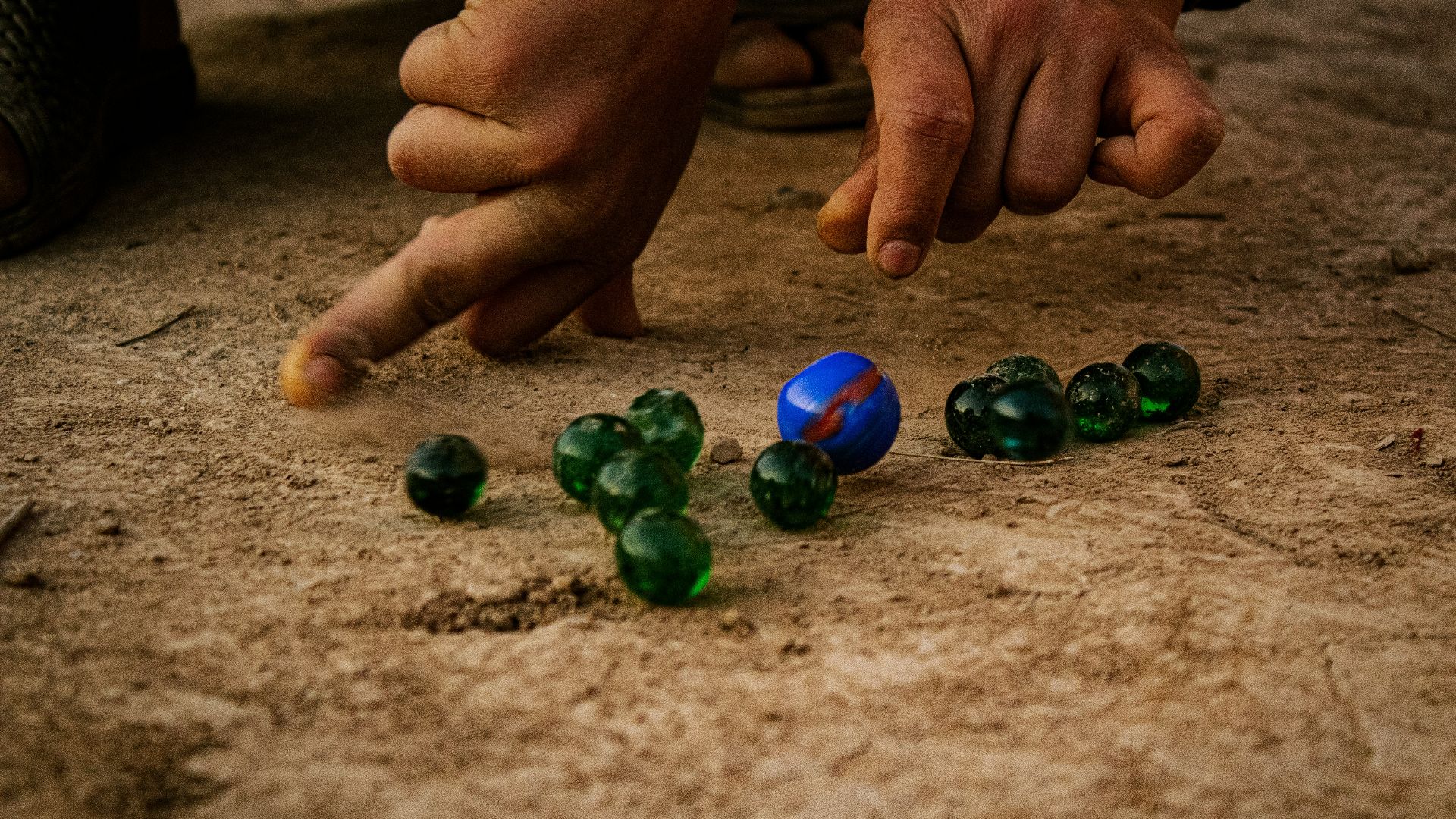 a man is playing with marbles on the ground