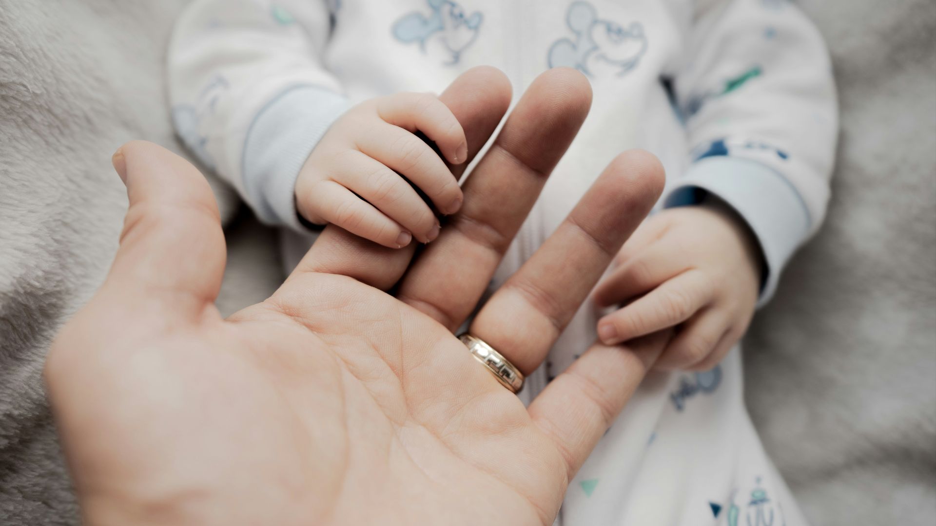 a person holding a baby's hand with a ring on it