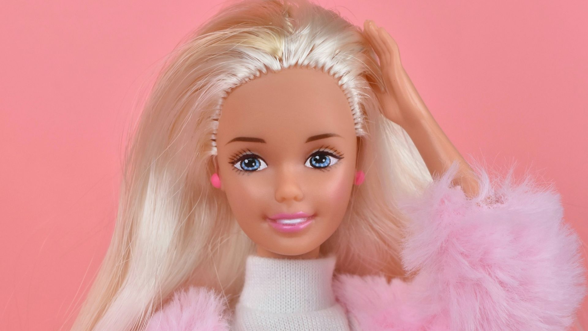 A barbie doll with blonde hair and pink pants