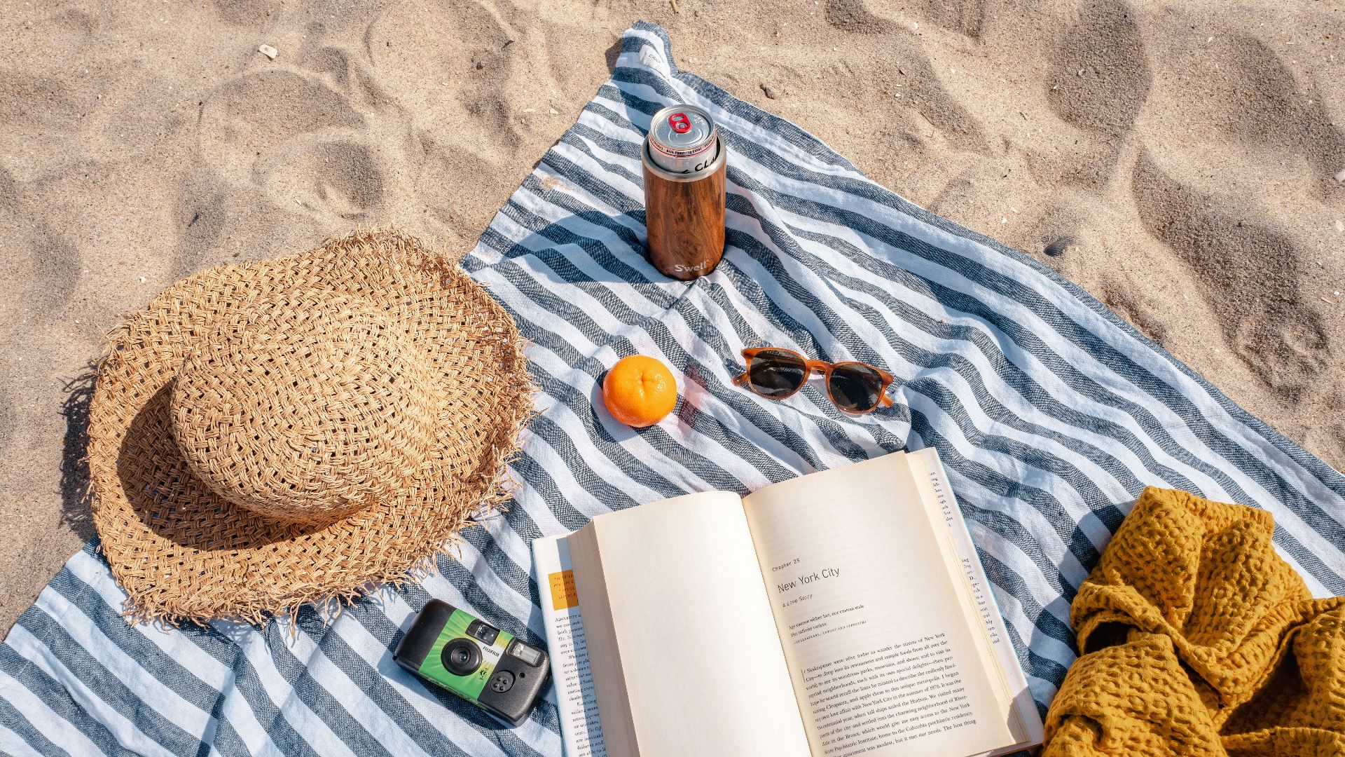 brown glass bottle beside white book on blue and white textile