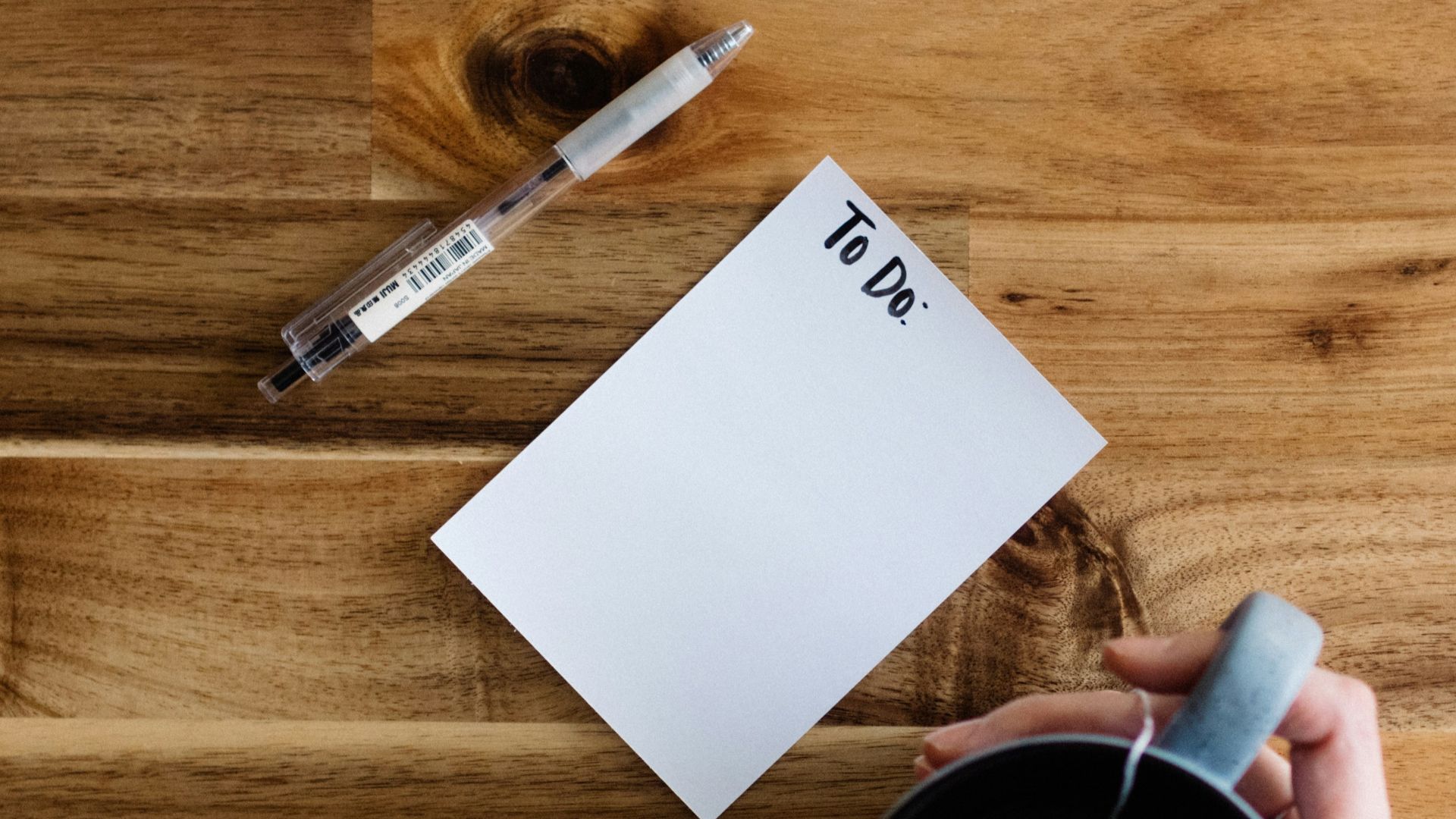 a person writing on a piece of paper next to a cup of coffee