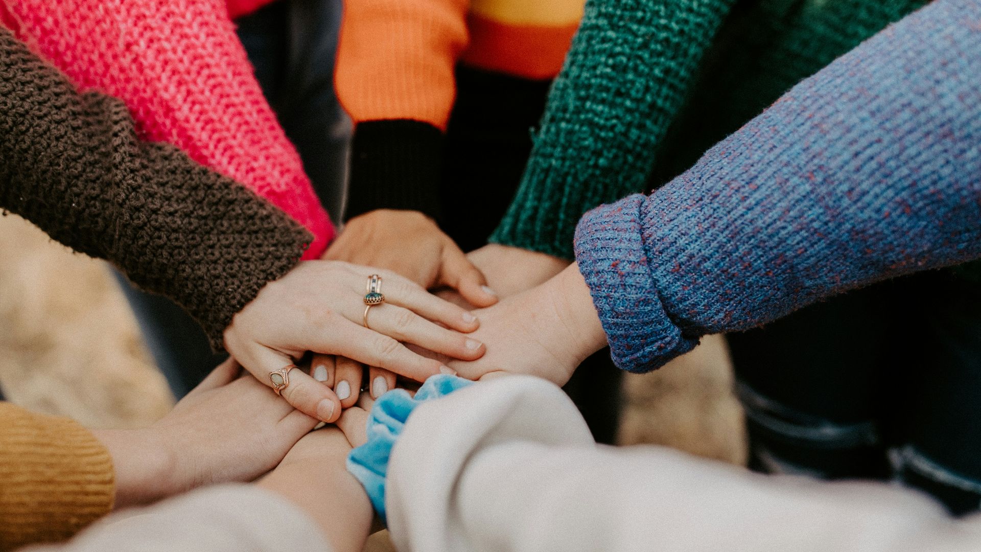 person in red sweater holding babys hand