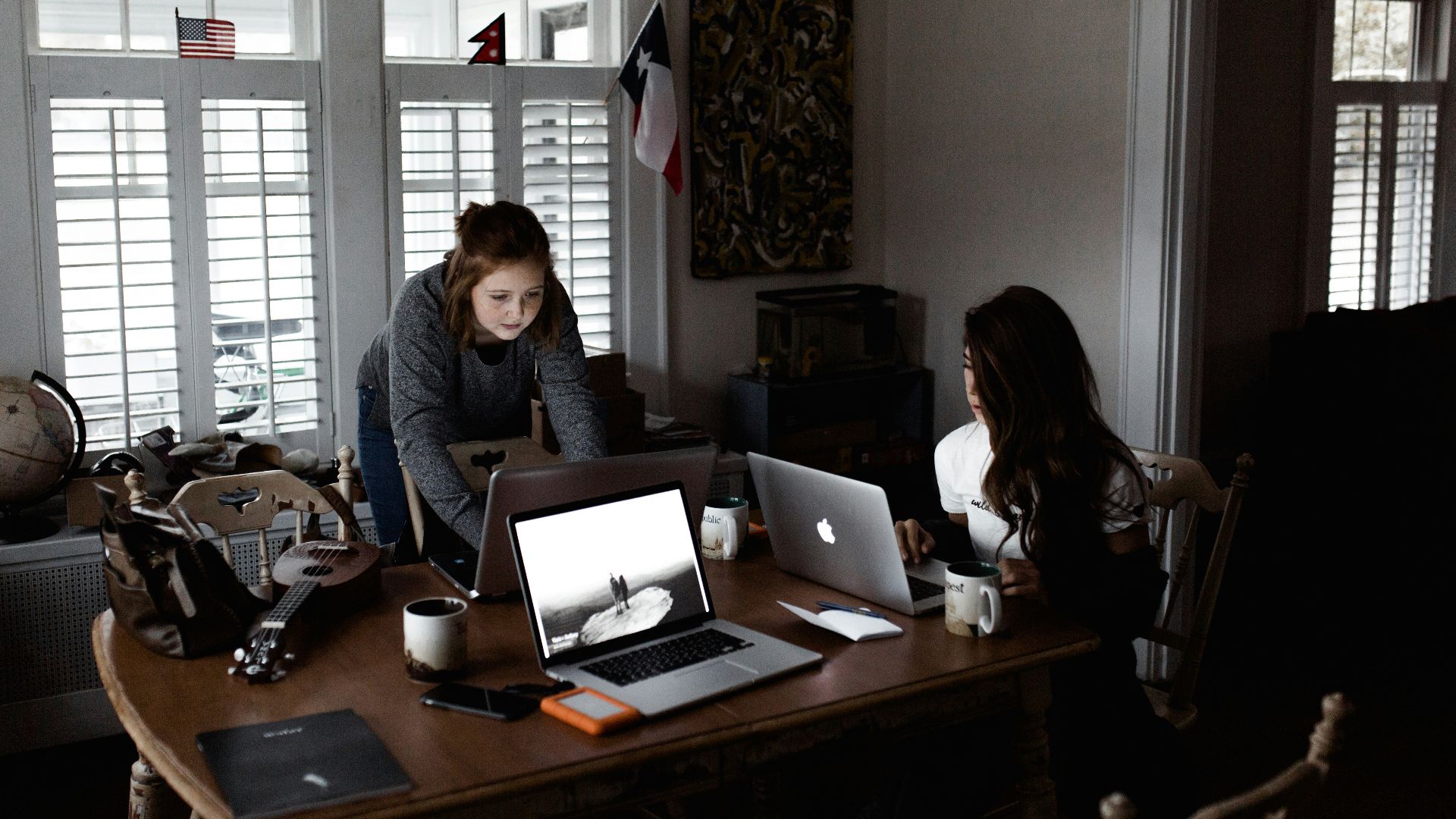 women using laptop on brown wooden table