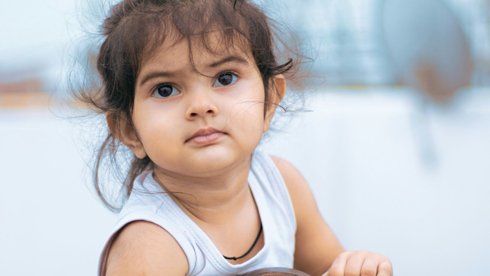 girl in white tank top sitting on brown wooden chair