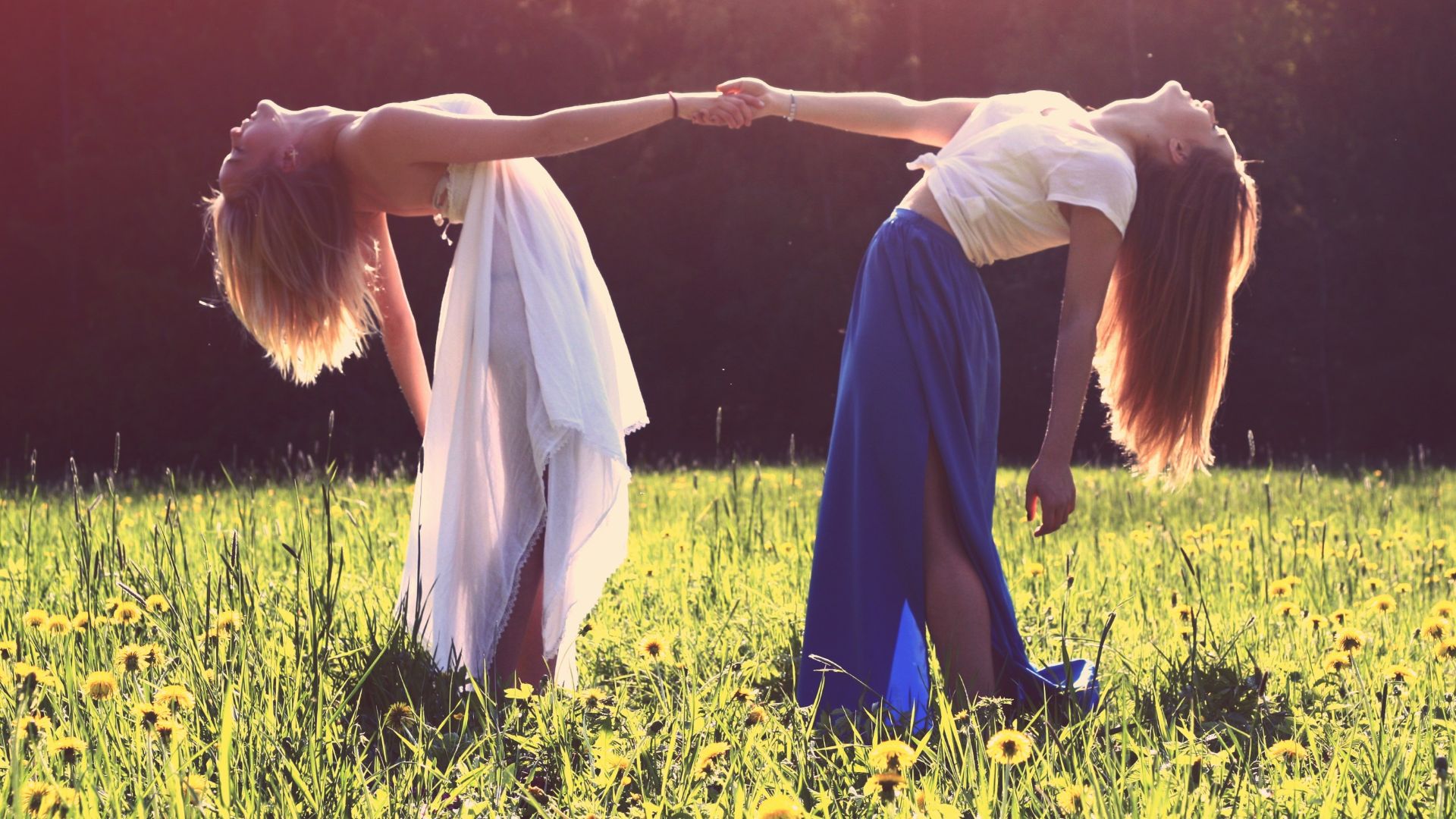 two women bending while holding hands