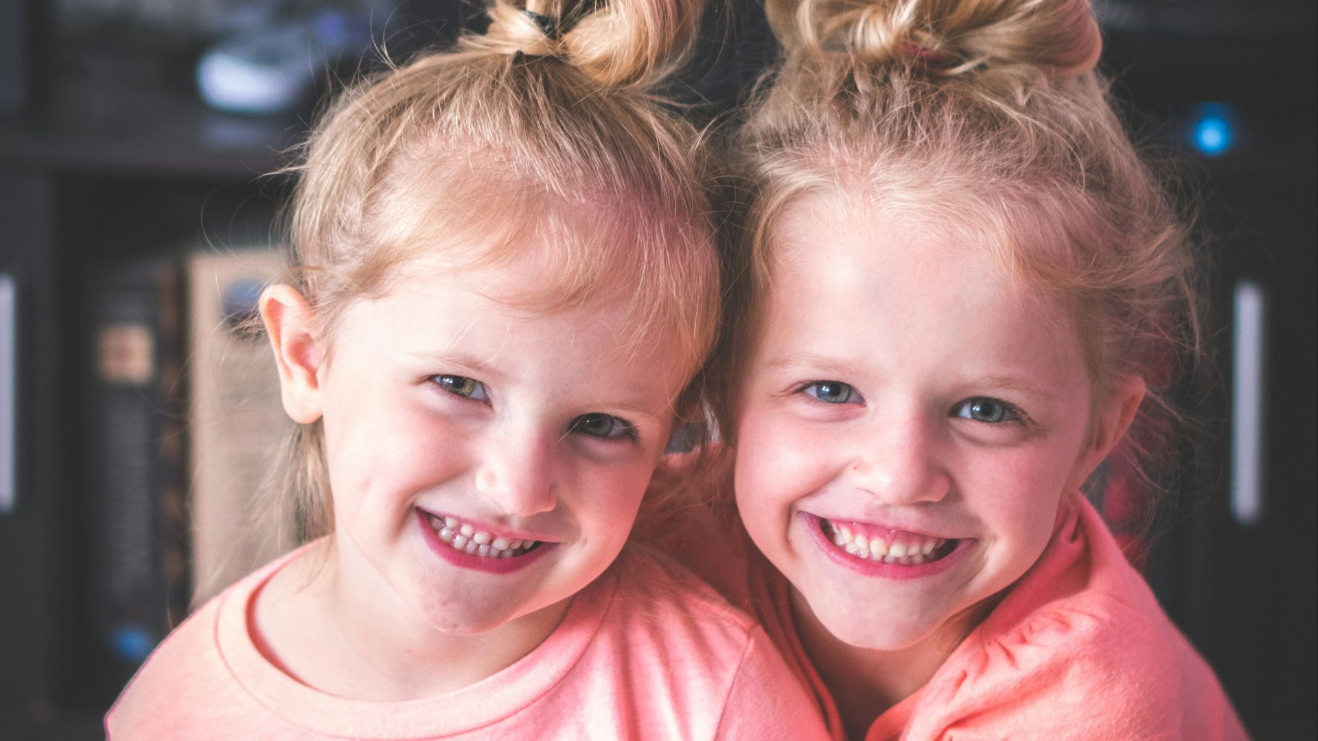 girl in pink crew neck t-shirt smiling beside girl in pink t-shirt