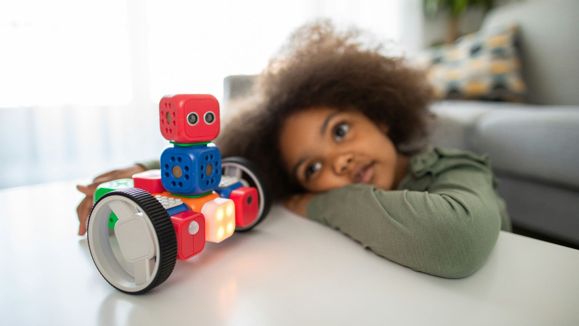 boy lying on bed playing with red and blue toy truck