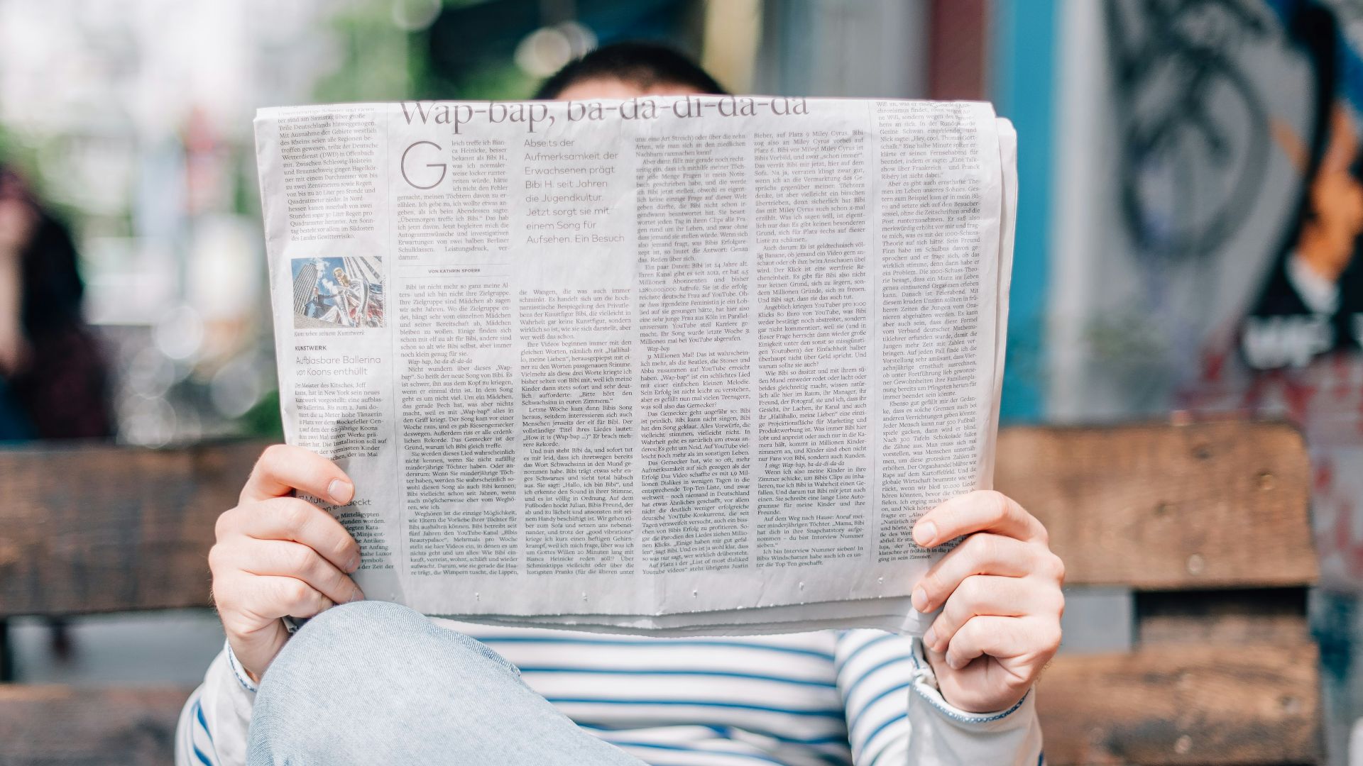 man sitting on bench reading newspaper