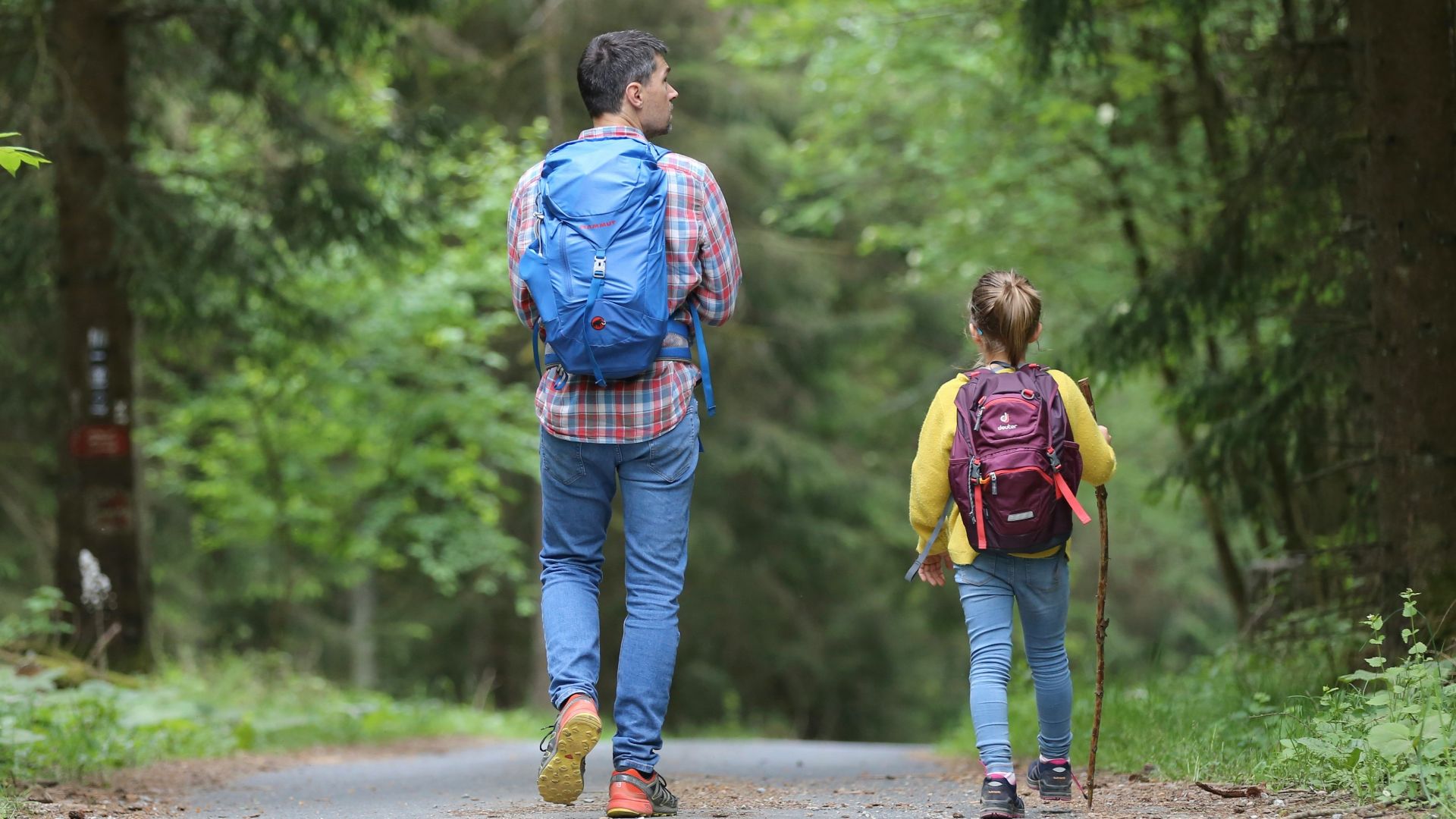 man in blue jacket and blue denim jeans walking on dirt road during daytime