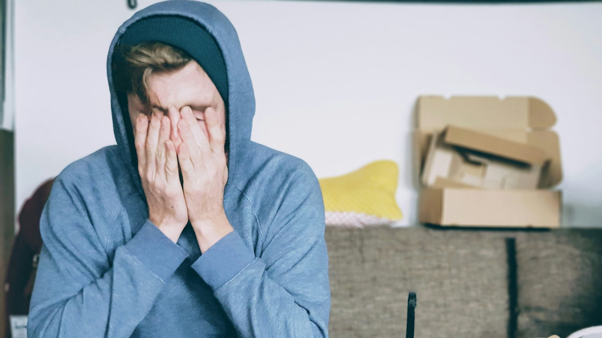 man covering face with both hands while sitting on bench