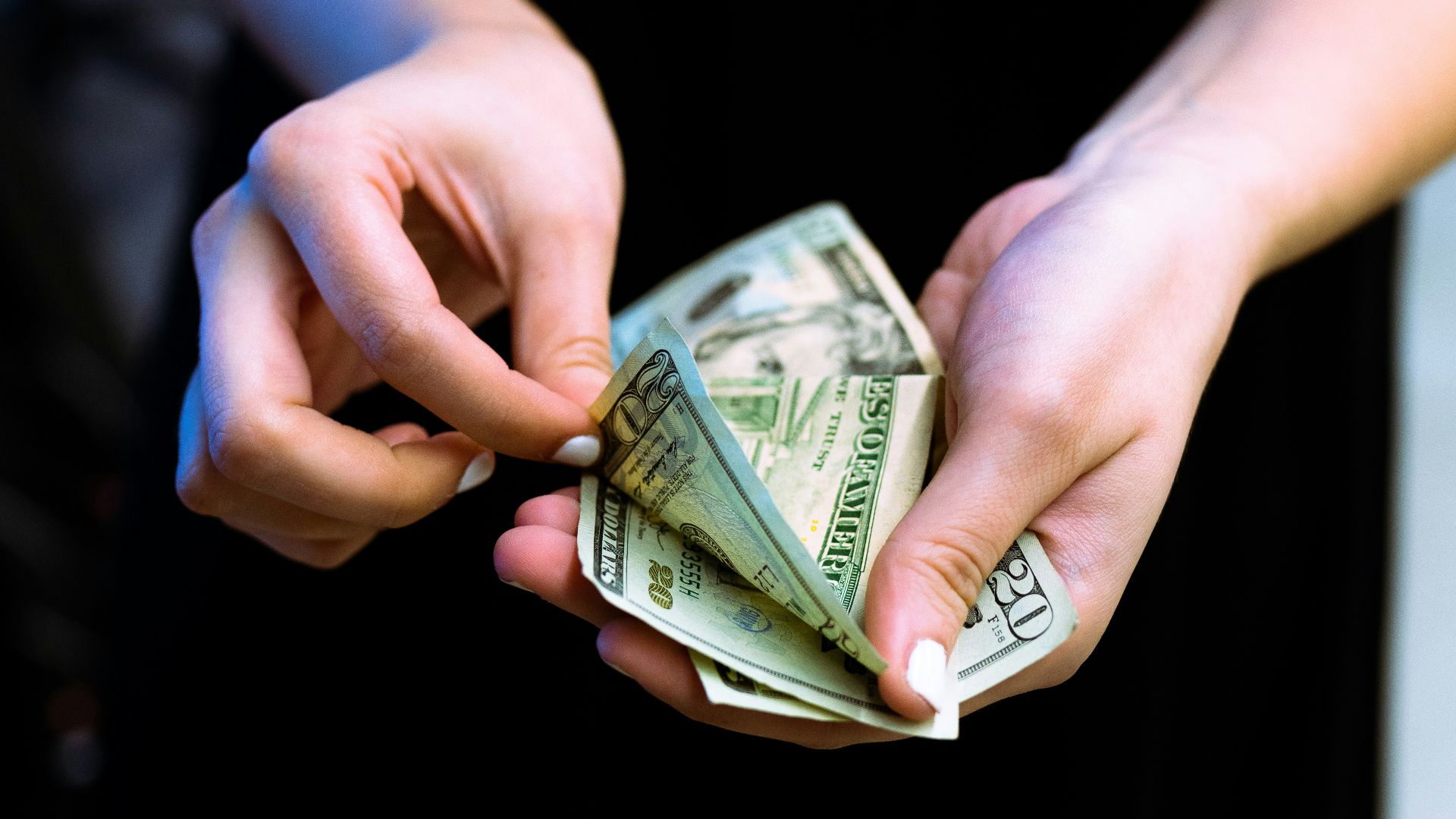 person holding fan of 100 us dollar bill