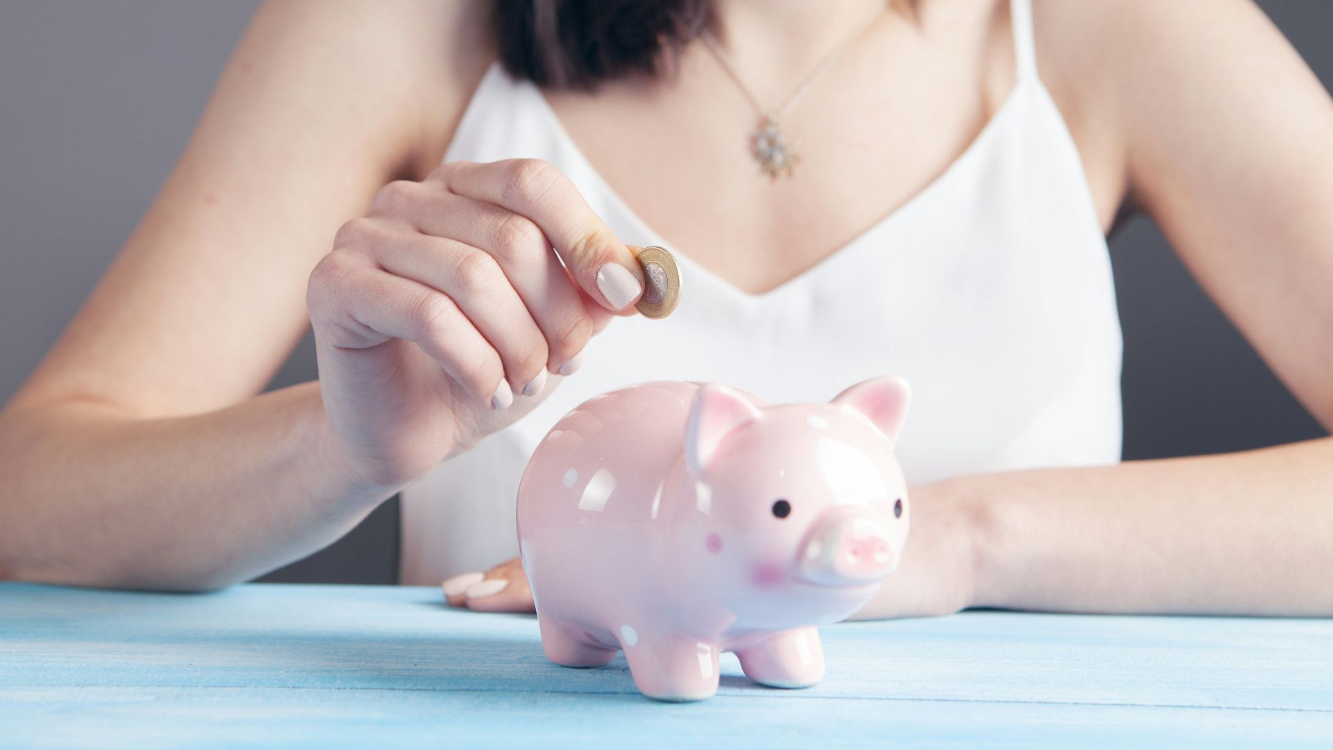 woman in white tank top holding pink pig figurine