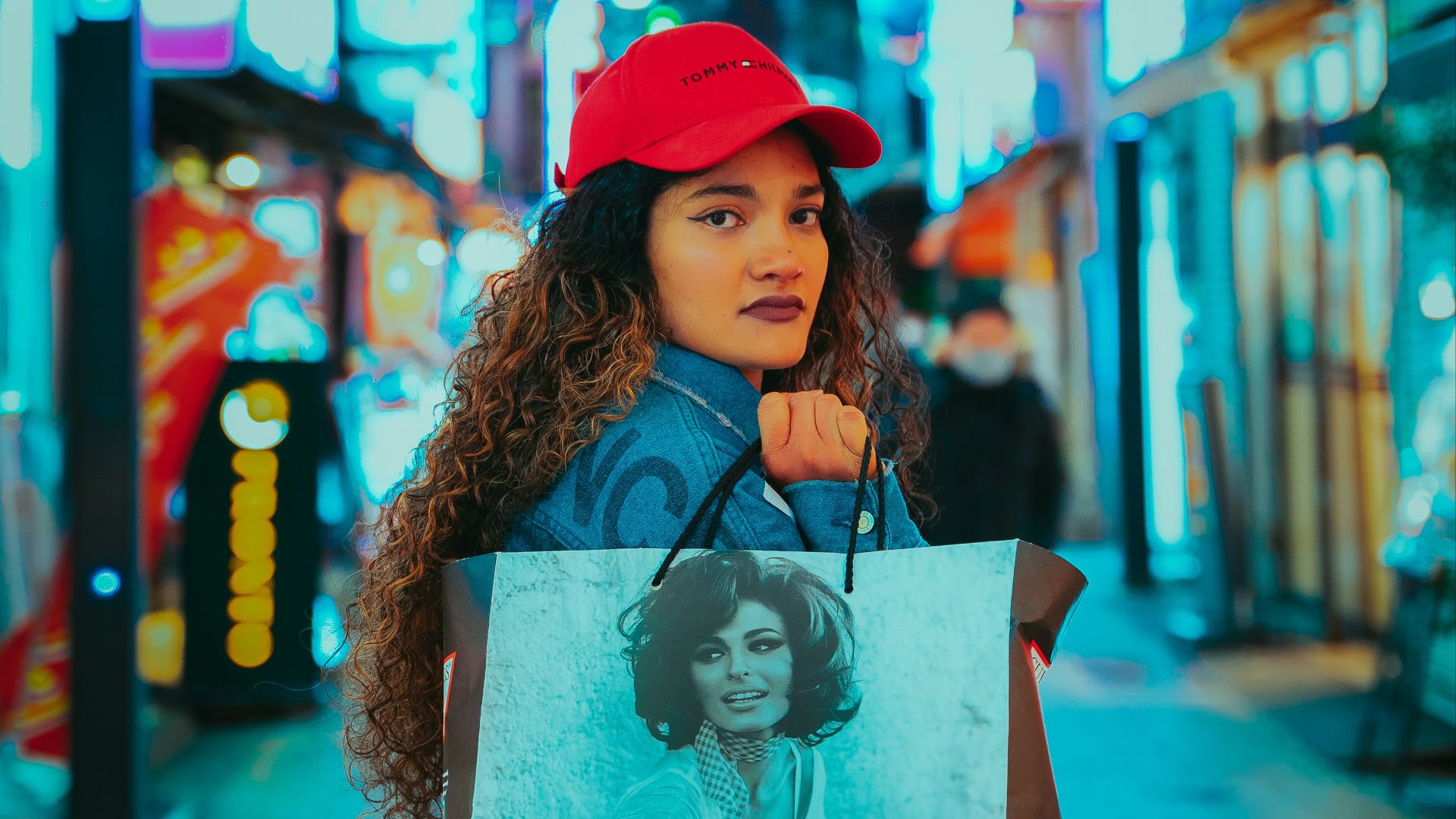 a woman holding a guess shopping bag on a city street