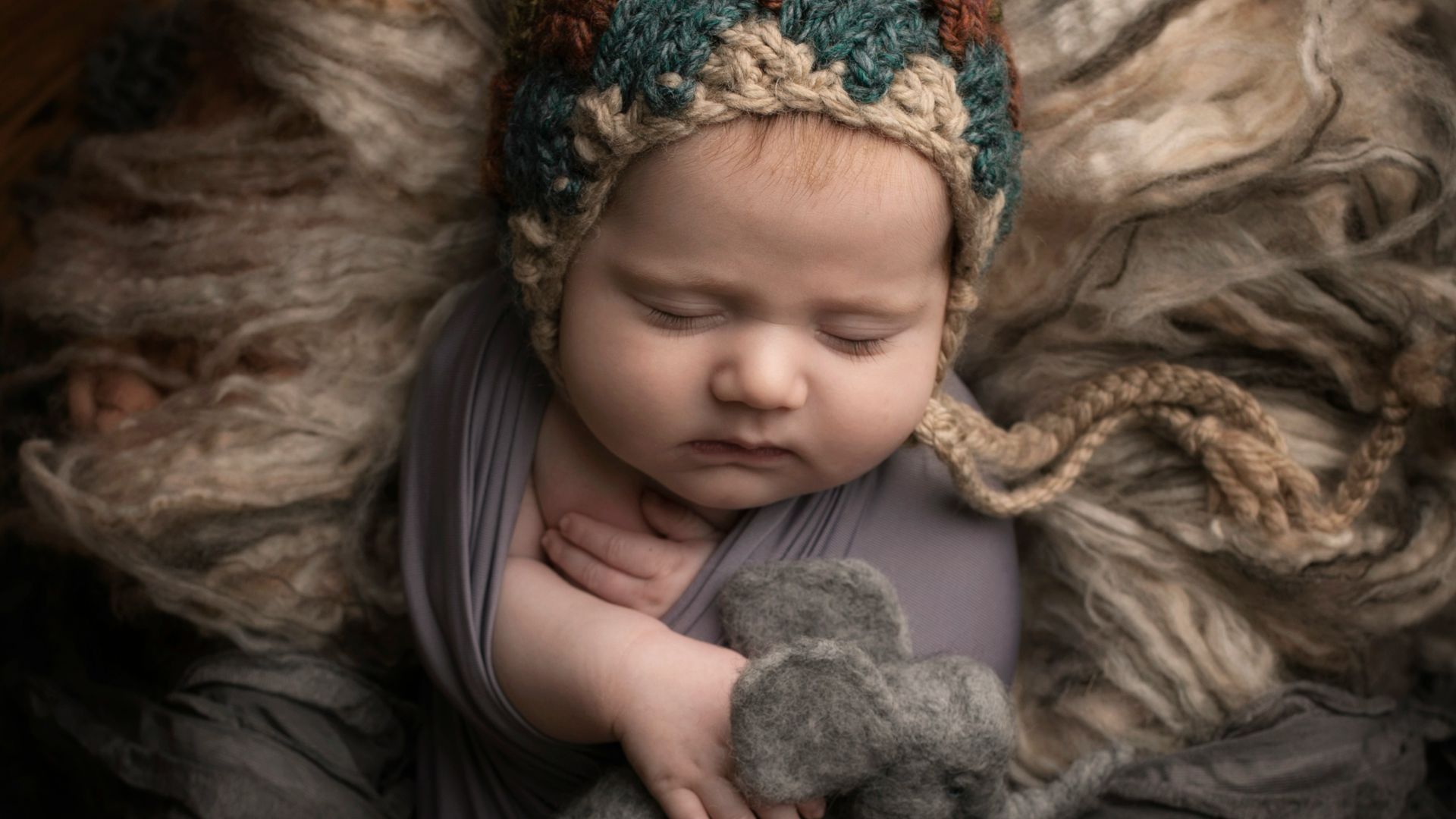 girl in grey long sleeve shirt lying on grey fur textile