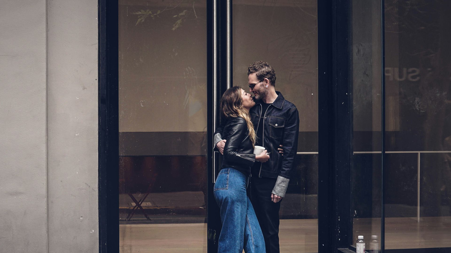 photo of man and woman kissing beside glass doors