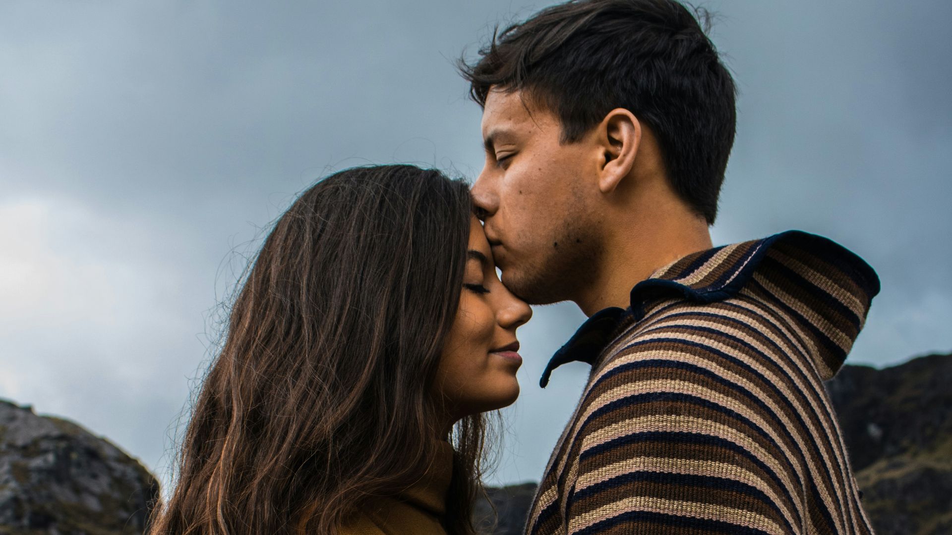 man kissing woman on forehead